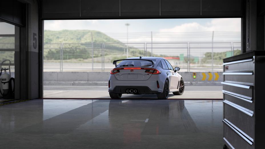 Official Honda photo of a Championship White Civic Type R rear with triple-exit exhaust in a pit garage