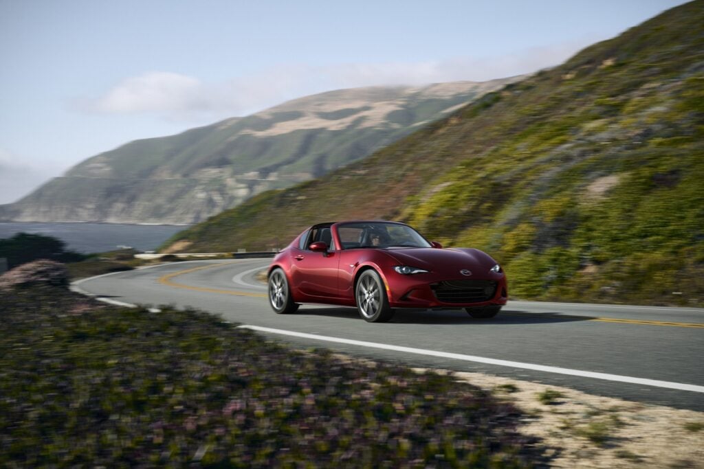 Official Mazda photo of a Soul Red Crystal Metallic 2026 MX-5 Miata RF on a coastal road