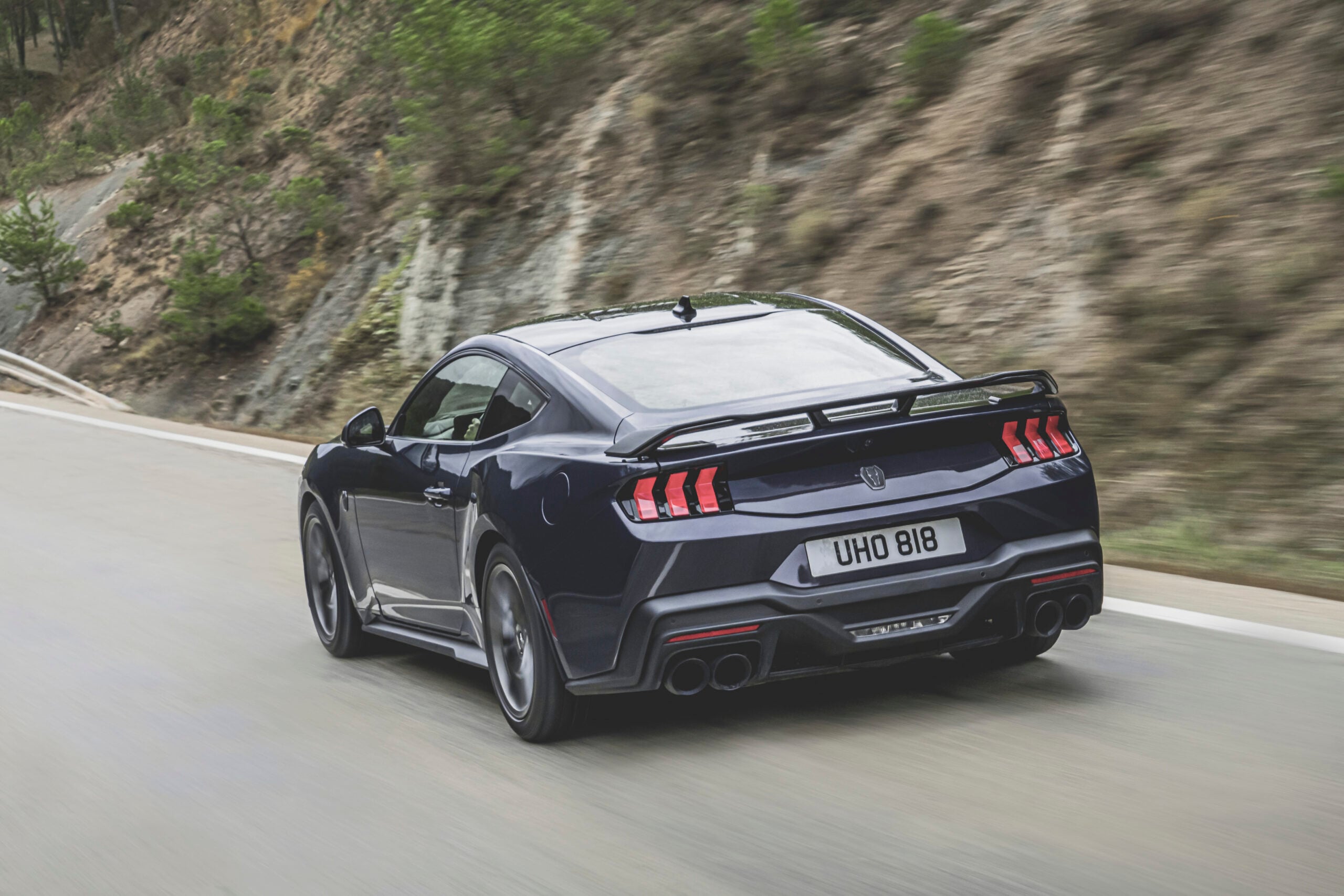 Official Ford photo of Mustang Dark Horse rear three-quarter on a mountain road