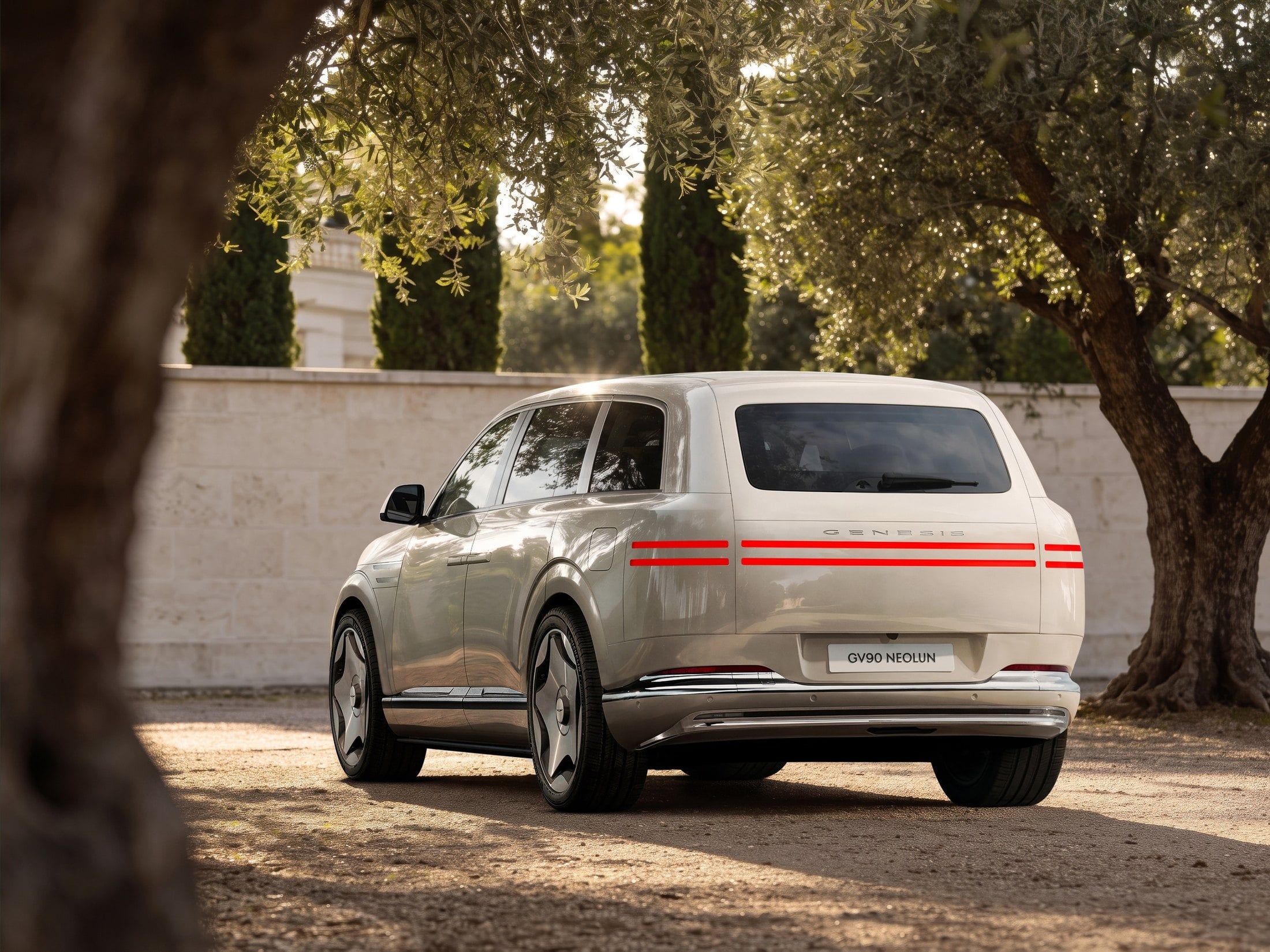 Rear three-quarter view of a cream Genesis GV90 with two-line taillights and Genesis lettering