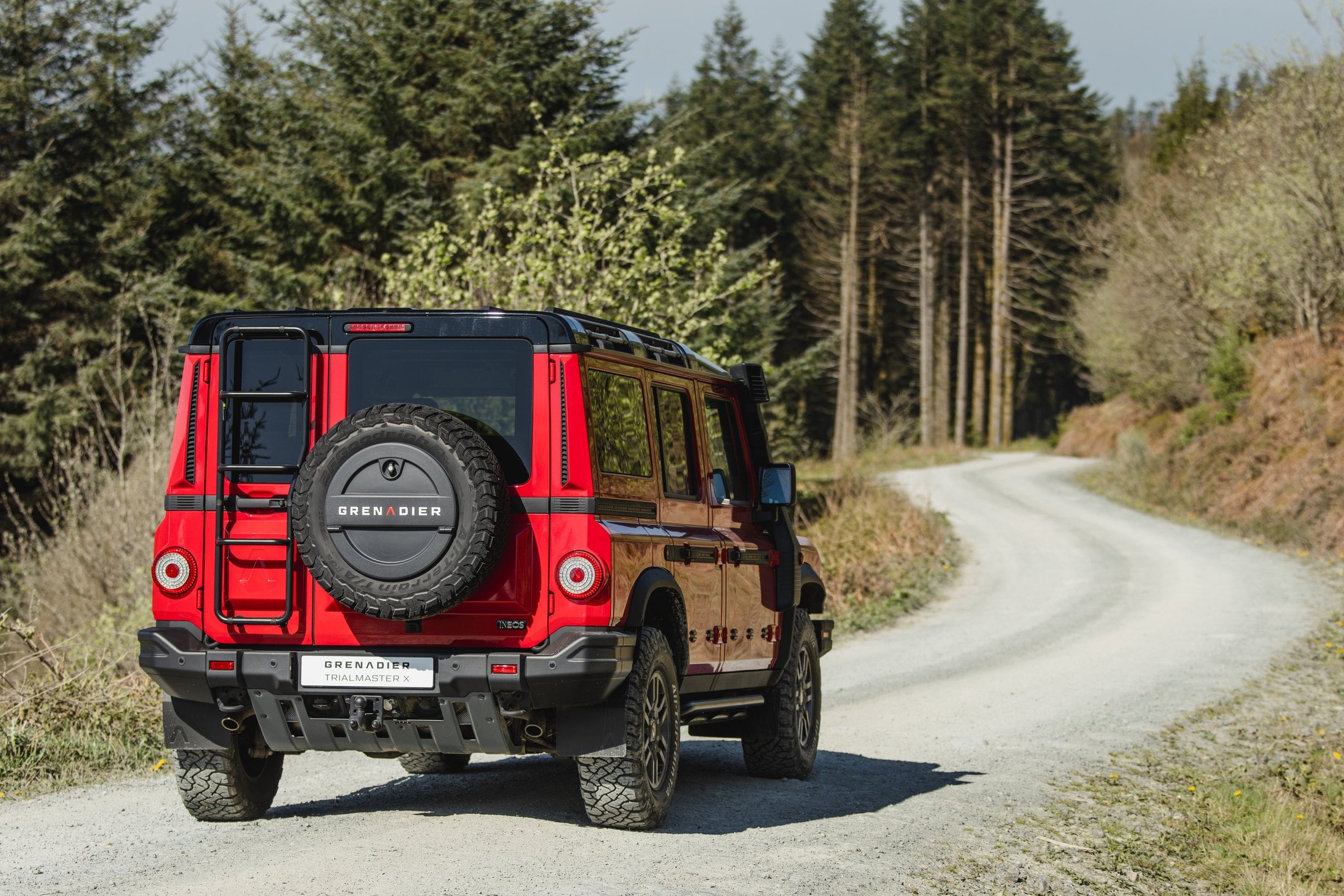 Official photo of the Devil Red INEOS Grenadier Trialmaster X, rear three-quarter with spare wheel and access ladder