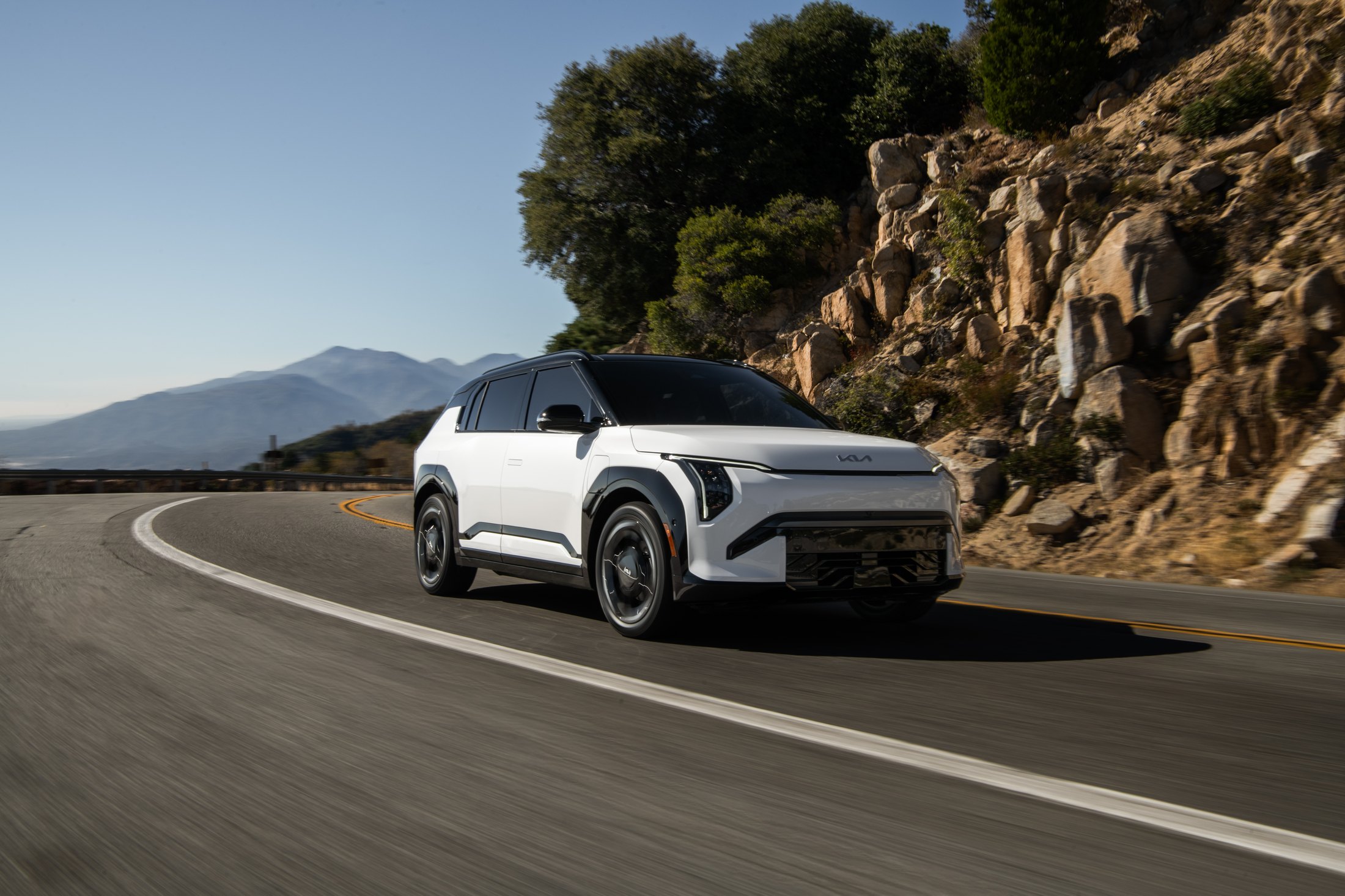 Official Kia photo of the 2027 EV3 driving on a winding mountain road