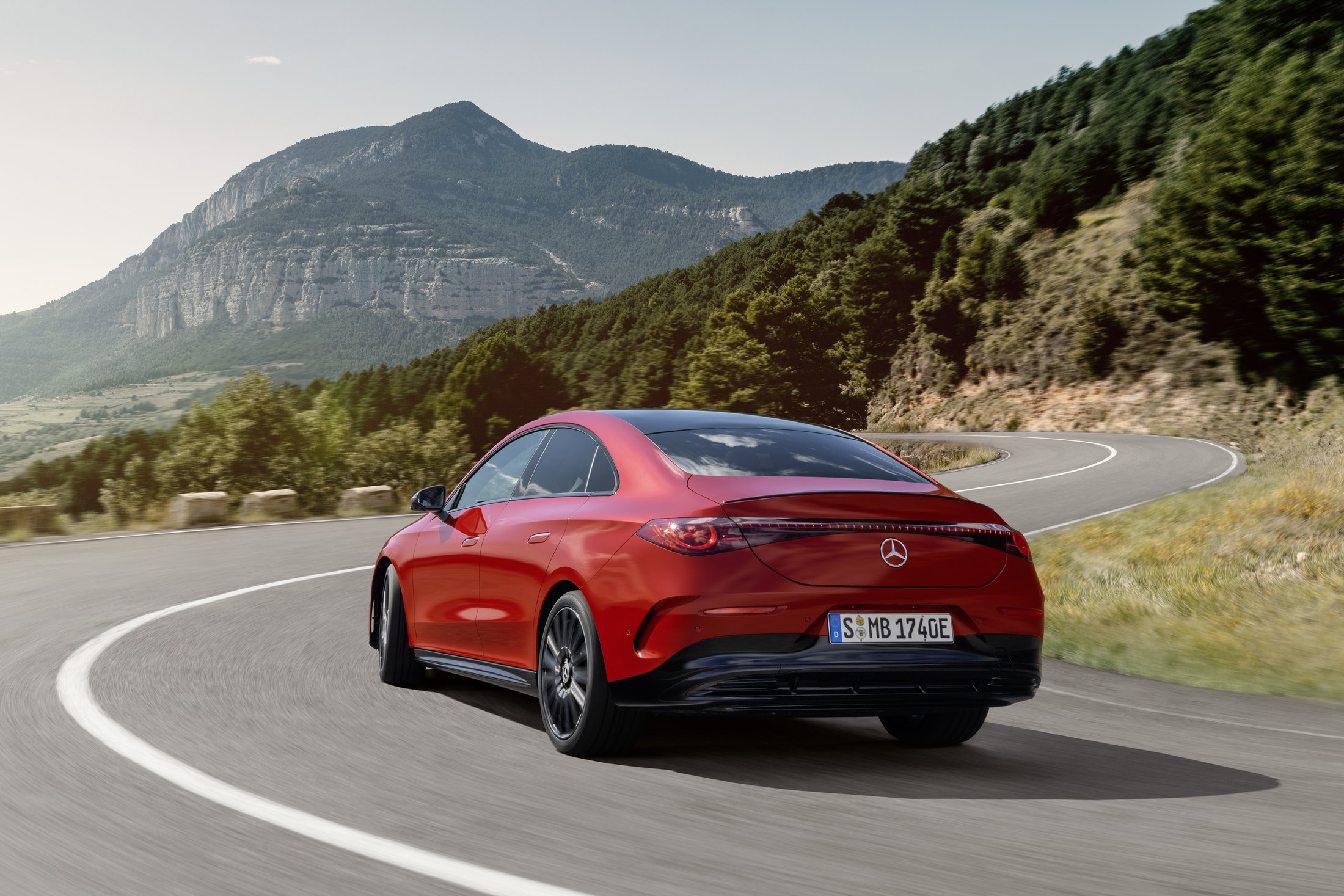 Official Mercedes-Benz photo of the electric CLA, rear three-quarter on a mountain road in Patagonia Red