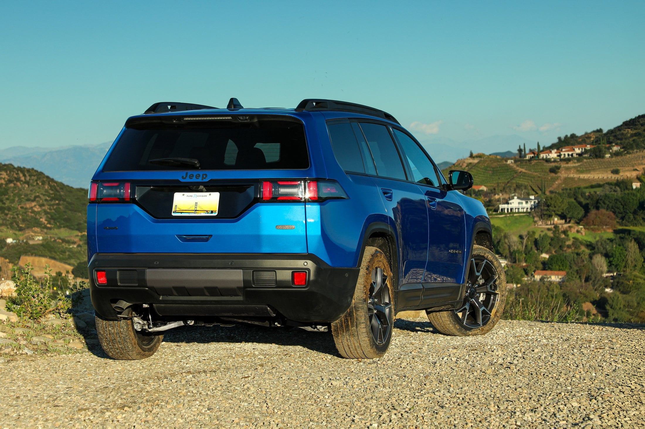 Official Jeep photo of the 2026 Cherokee, rear three-quarter in blue on a gravel path