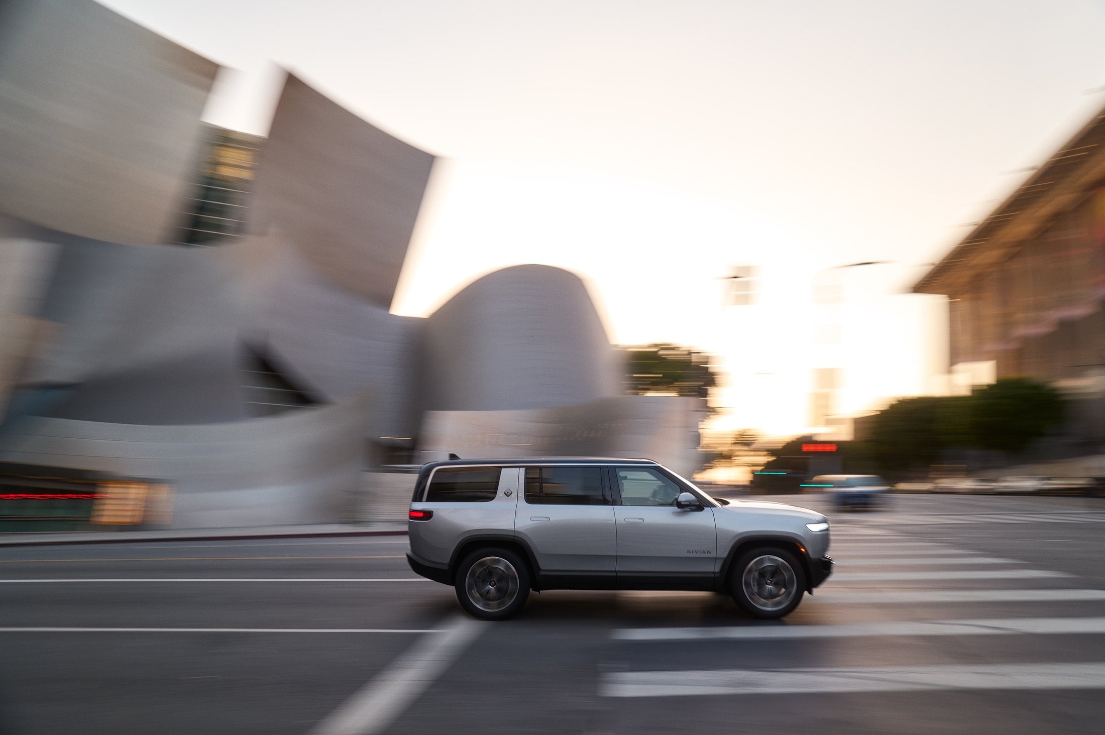 Official Rivian photo of the 2027 R1S in Esker Silver, side profile in motion