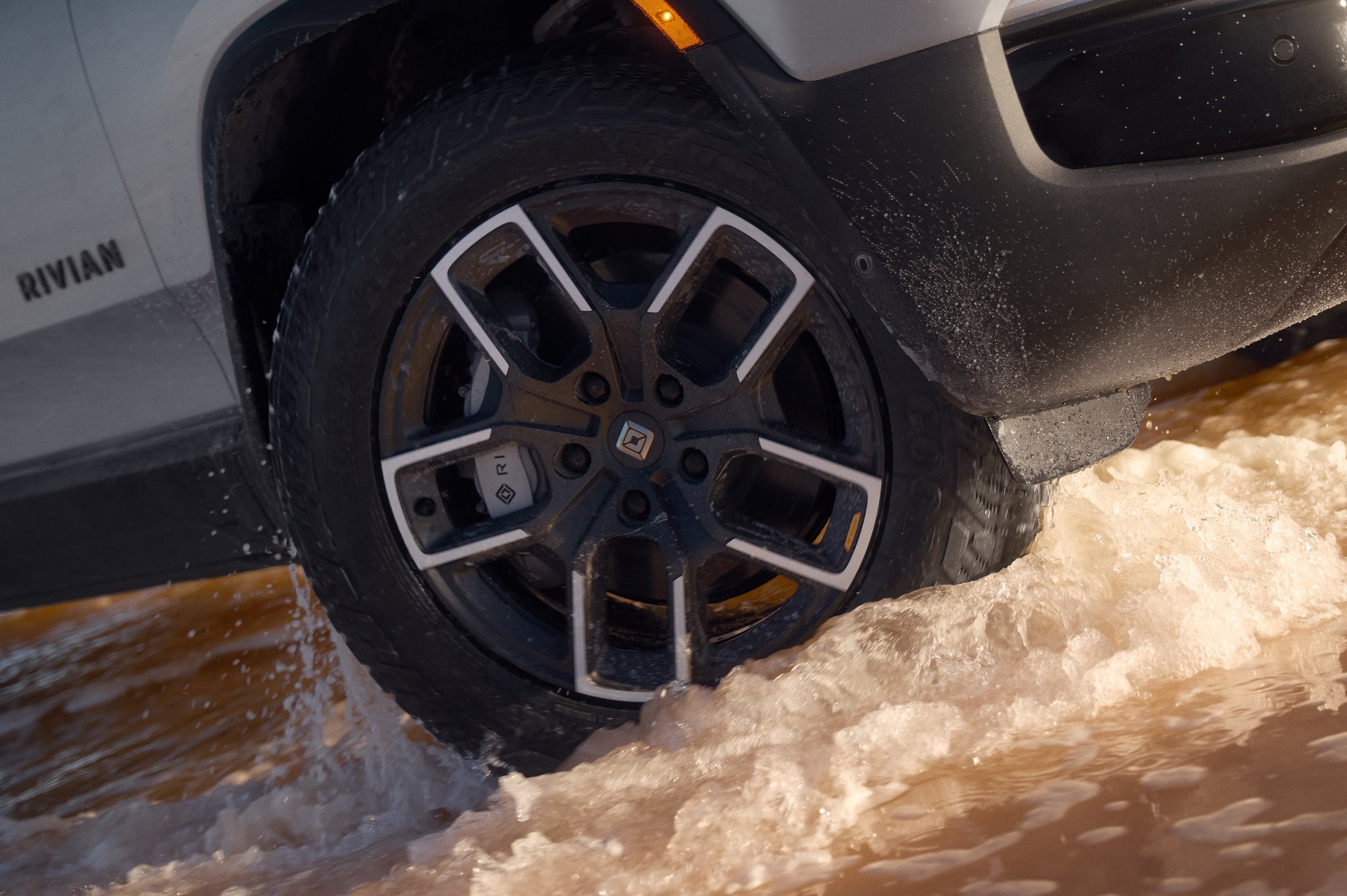 Official Rivian photo of the 2027 R1T 20-inch Adventure All-Season wheel and Goodyear tire splashing through water