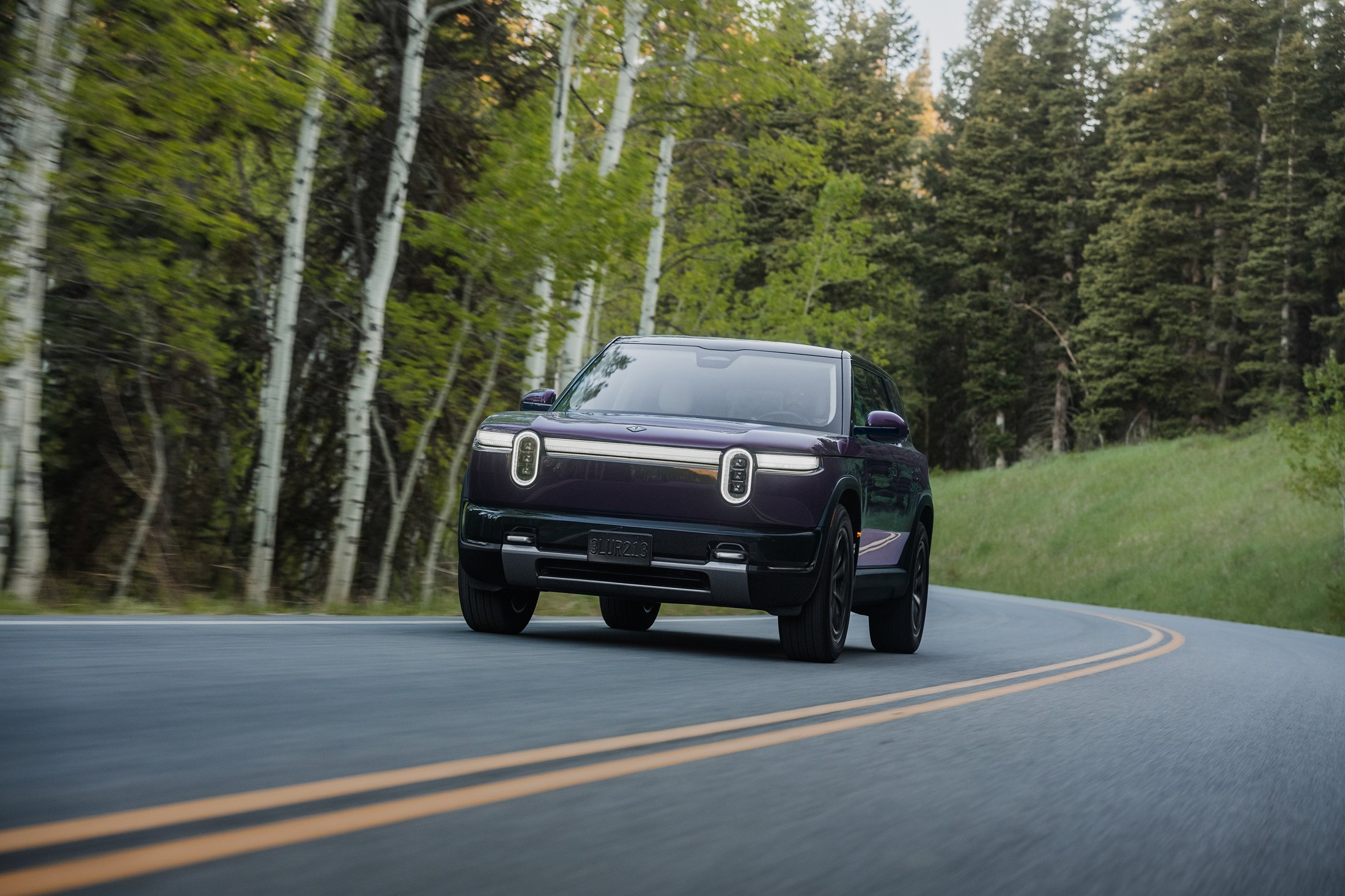 Official Rivian photo of the R2 driving on a winding mountain road