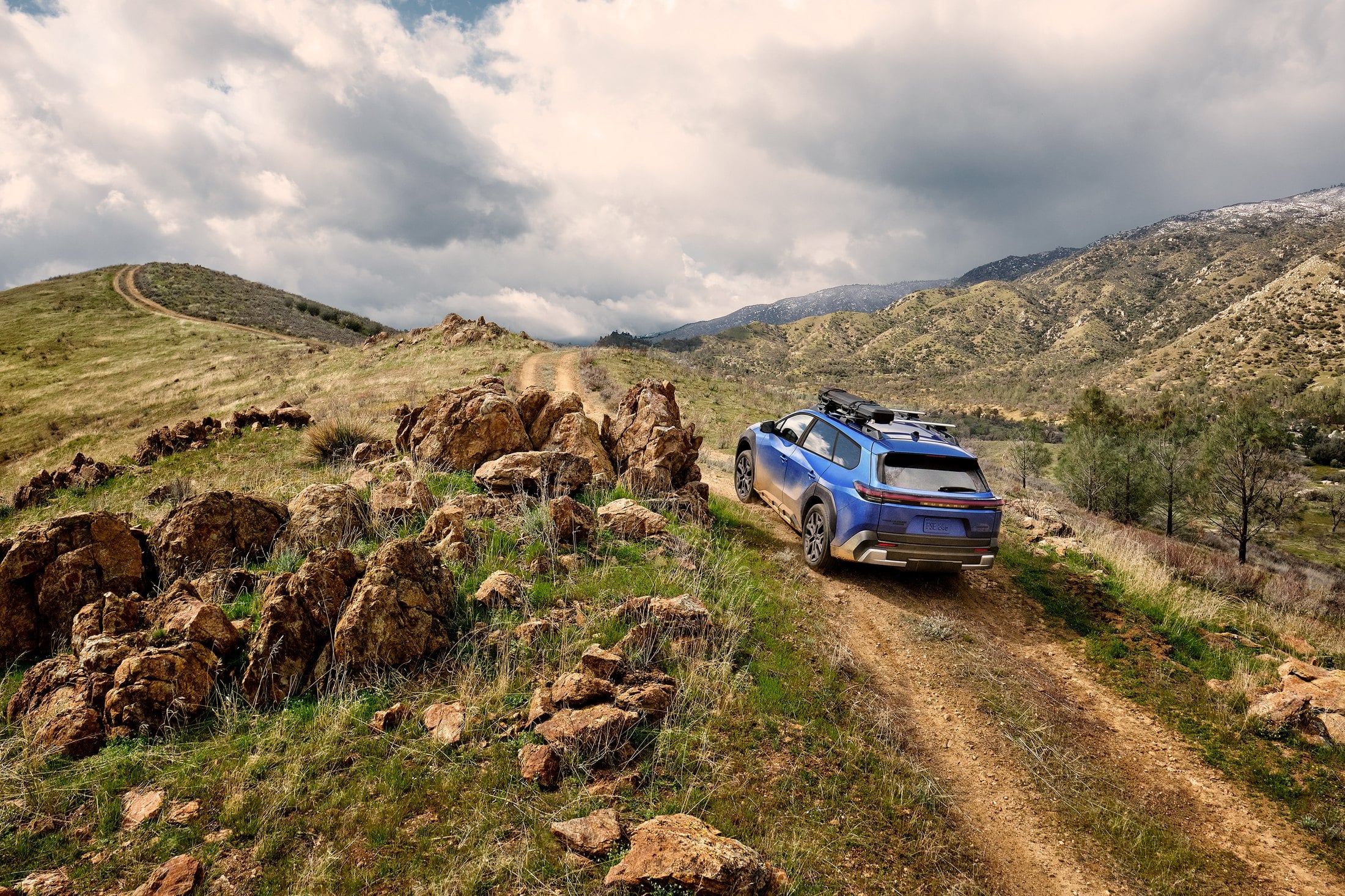 Official Subaru photo of the 2027 Trailseeker, rear three-quarter climbing a dirt trail