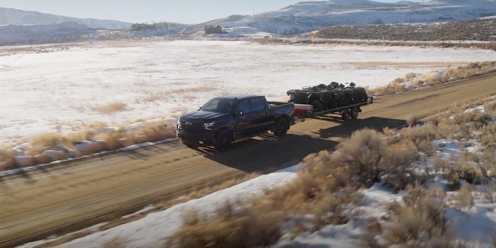 Official Chevrolet photo of a 2026 Silverado 1500 Crew Cab towing a dual-axle trailer loaded with ATVs on a dirt road