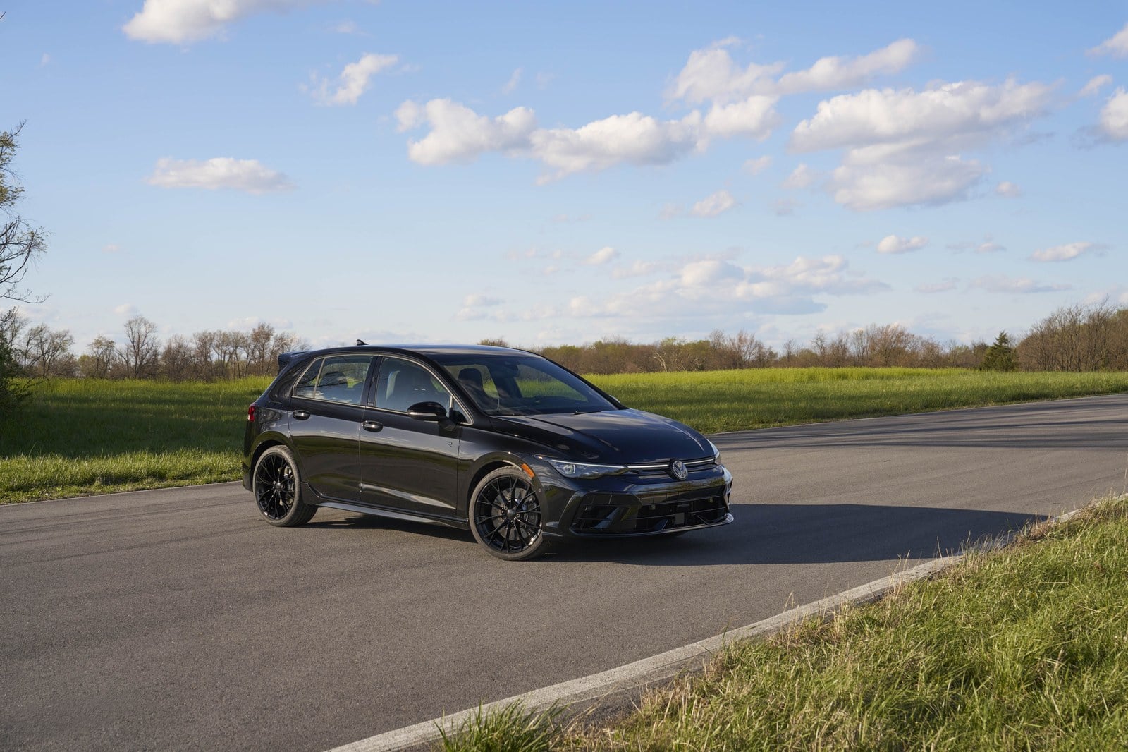 Official Volkswagen photo of a Mythos Black Golf R parked front three-quarter on a rural road