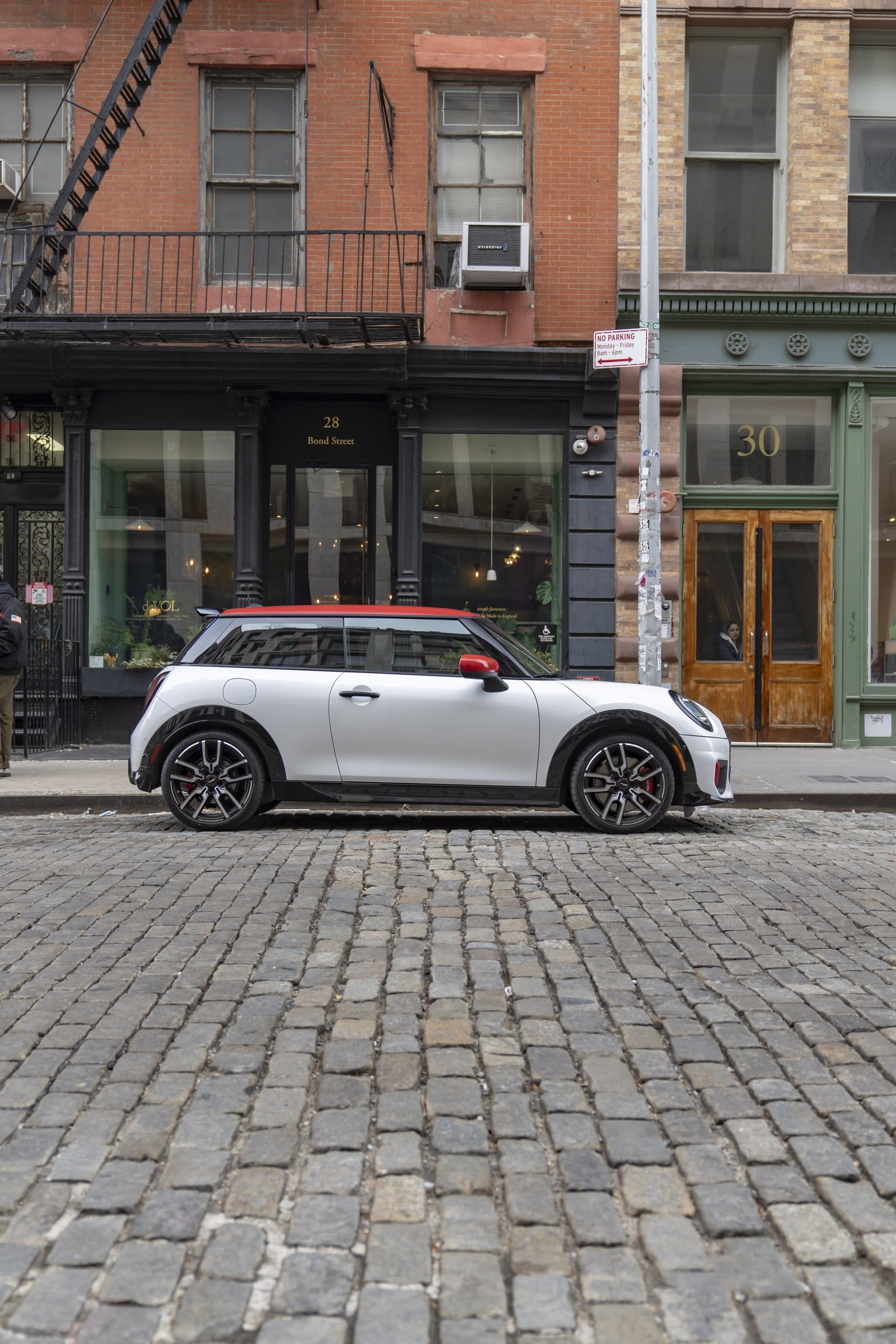 Official MINI photo of a JCW 2 Door side profile with red contrast roof on a city street