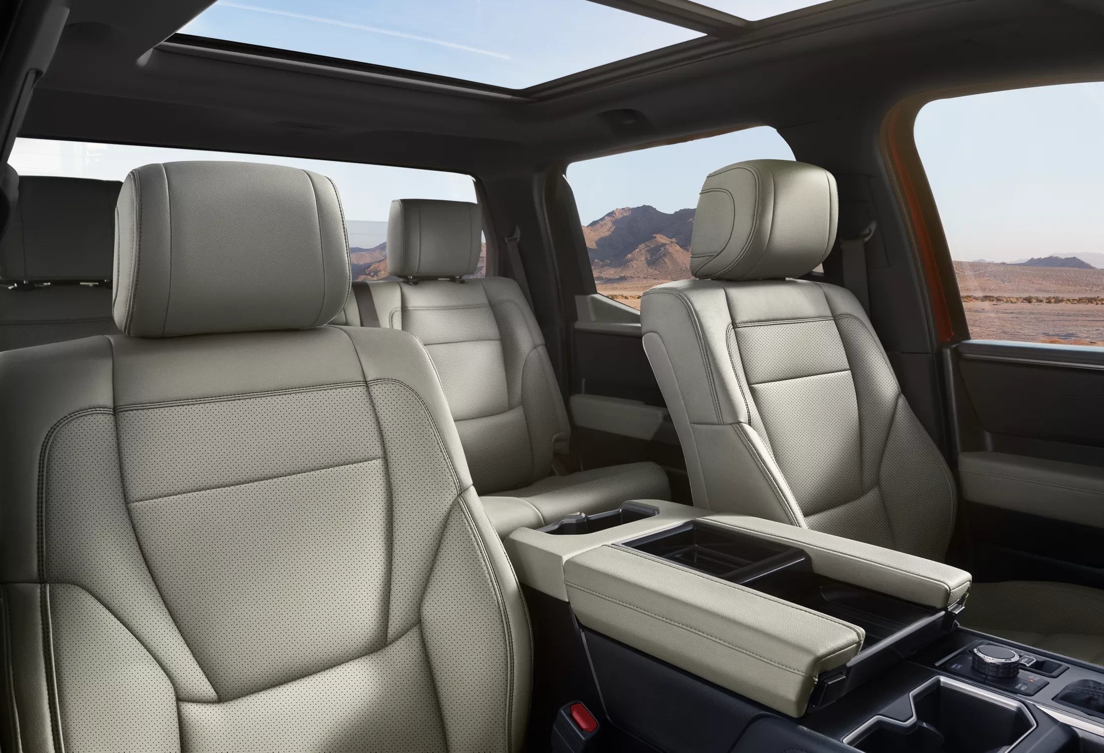 Official Toyota photo of a 2026 Tundra cabin with light leather, a wide center console, and a panoramic roof over desert mountains