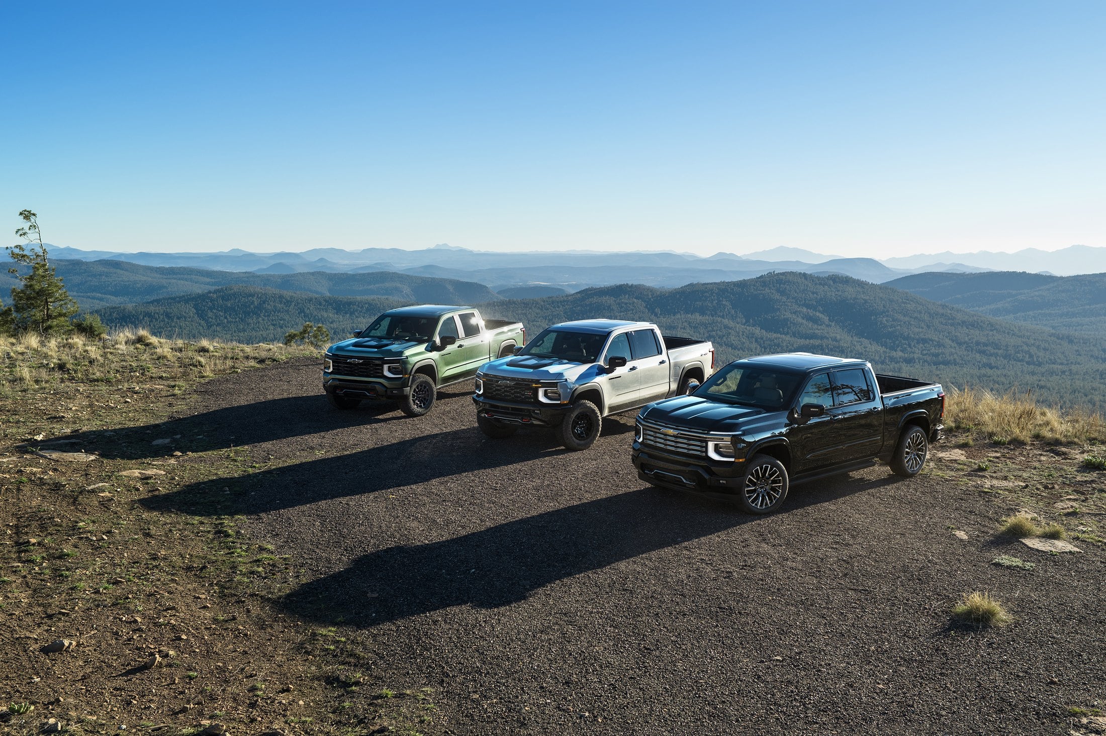 Official Chevrolet 2027 Silverado 1500 pack shot of Trail Boss, ZR2, and High Country at a mountain overlook