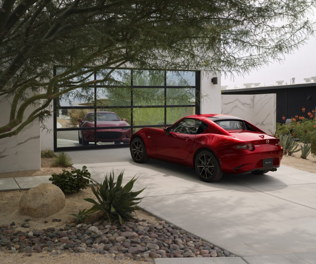 Official Mazda photo of Soul Red Crystal Metallic 2026 MX-5 Miata RF rear three-quarter at a modern house
