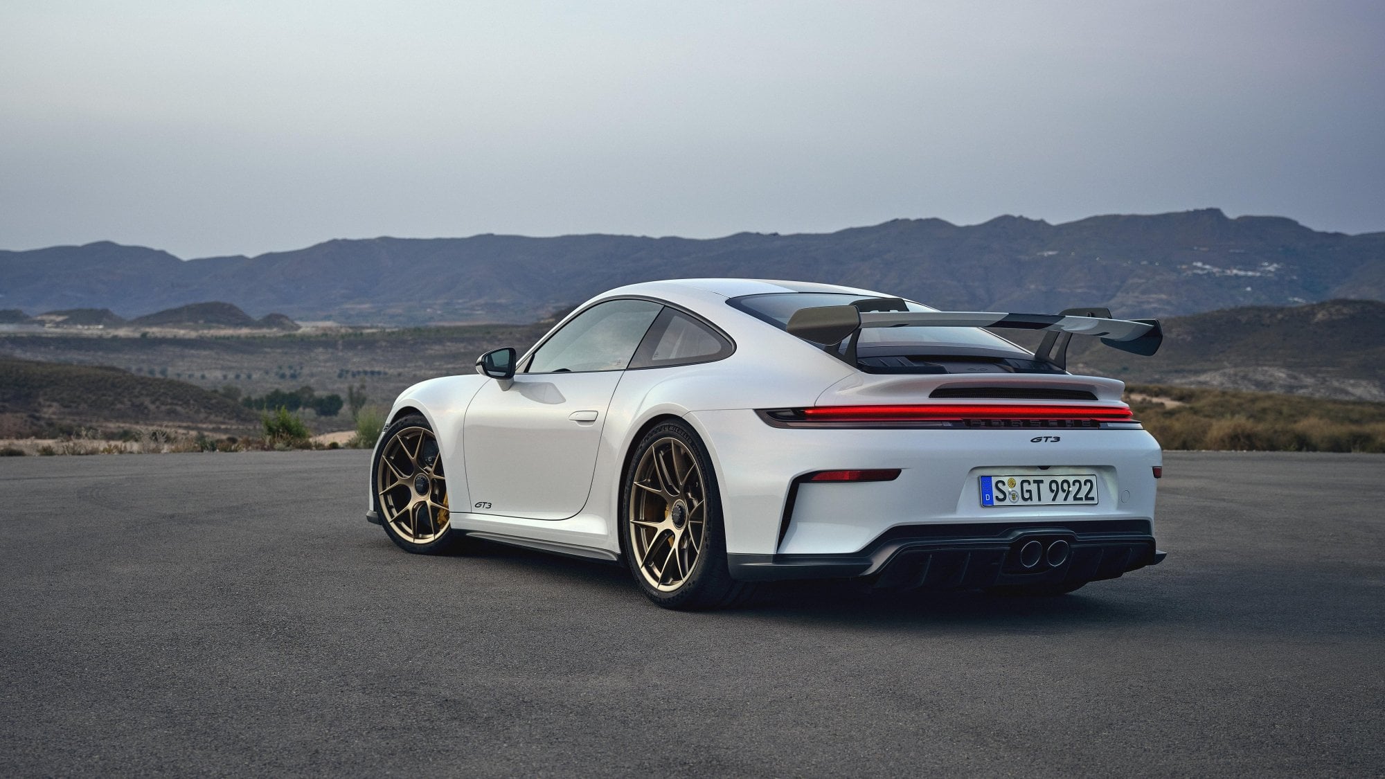 Official Porsche photo of a 2026 911 GT3 with fixed rear wing rear three-quarter in white