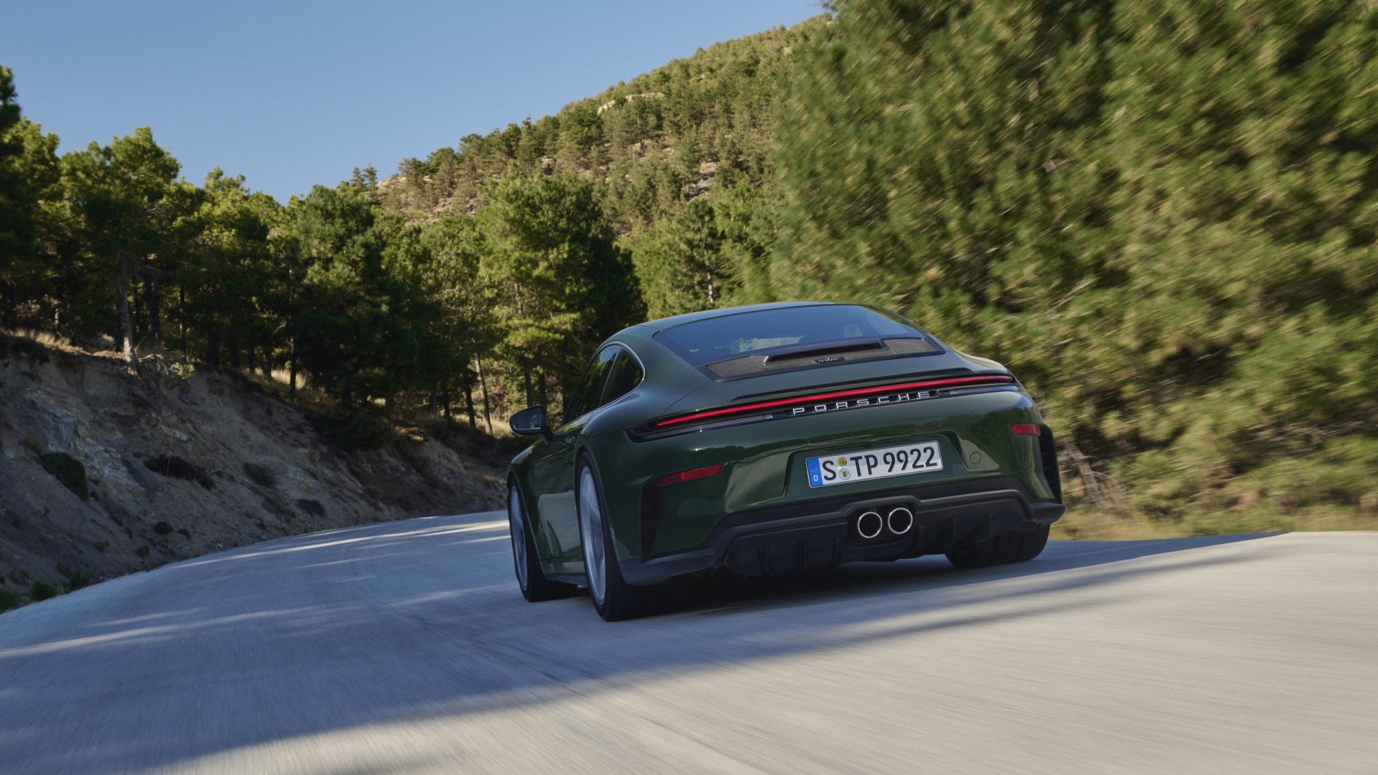 Official Porsche photo of a 2026 911 GT3 with Touring Package rear three-quarter driving on a mountain road