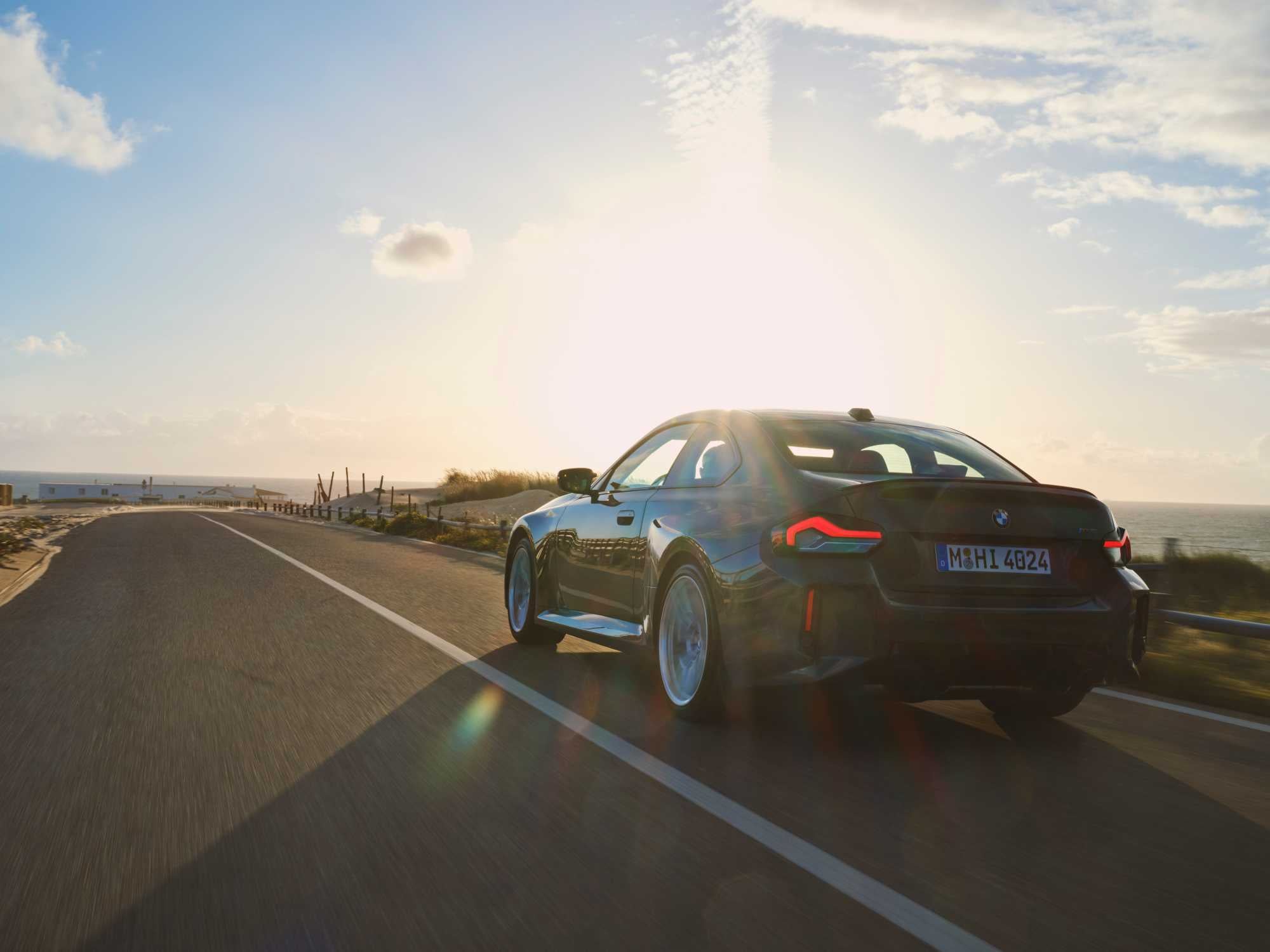Official BMW photo of a dark green BMW M2 Coupe rear three-quarter at sunset