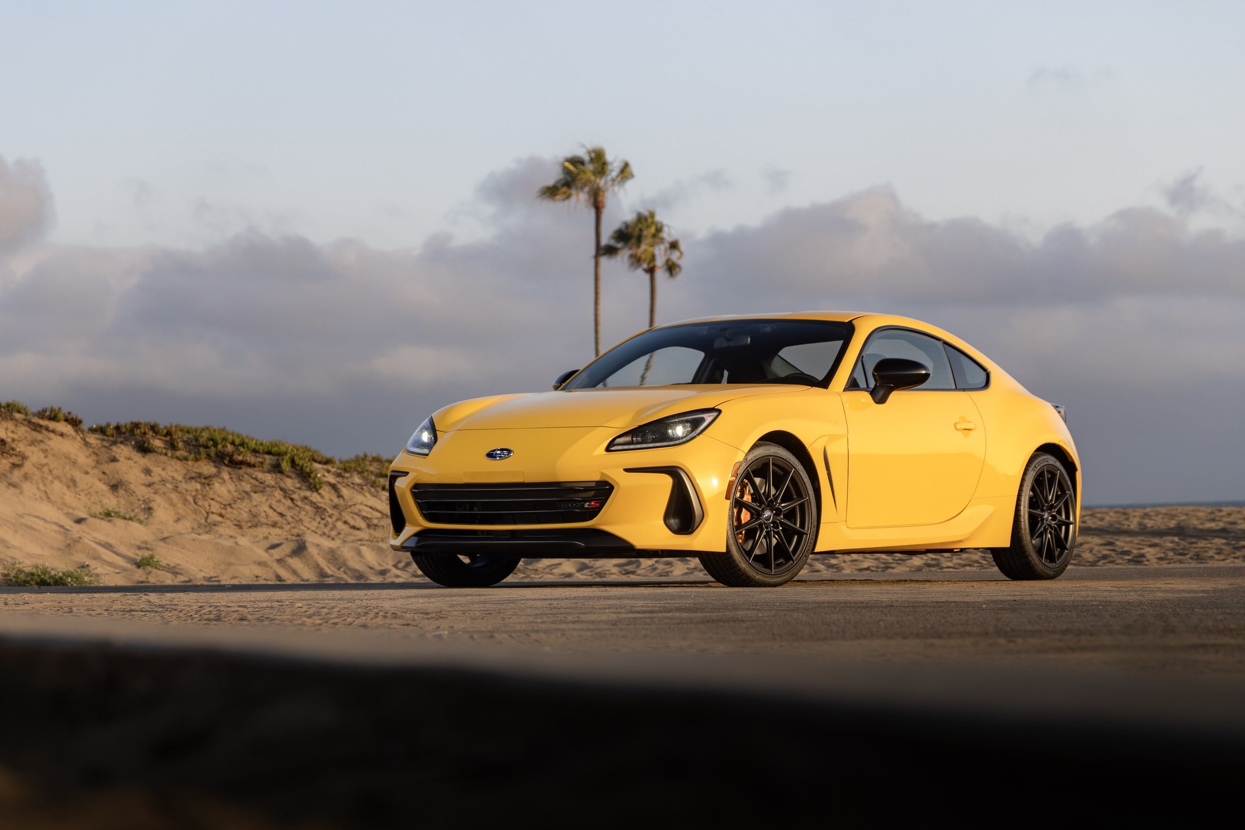 Official Subaru photo of a Sunrise Yellow BRZ tS front three-quarter on a coastal road