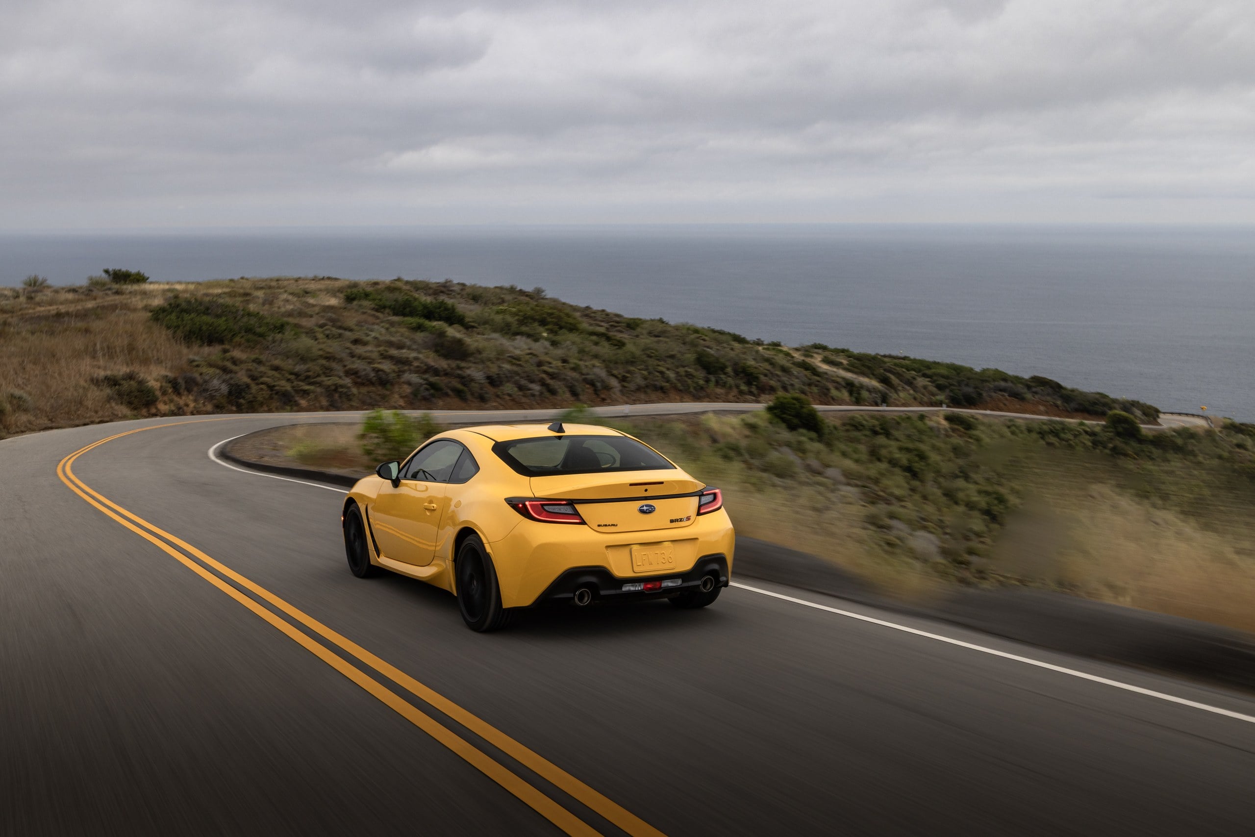 Official Subaru photo of a Sunrise Yellow BRZ tS driving a coastal ridge road