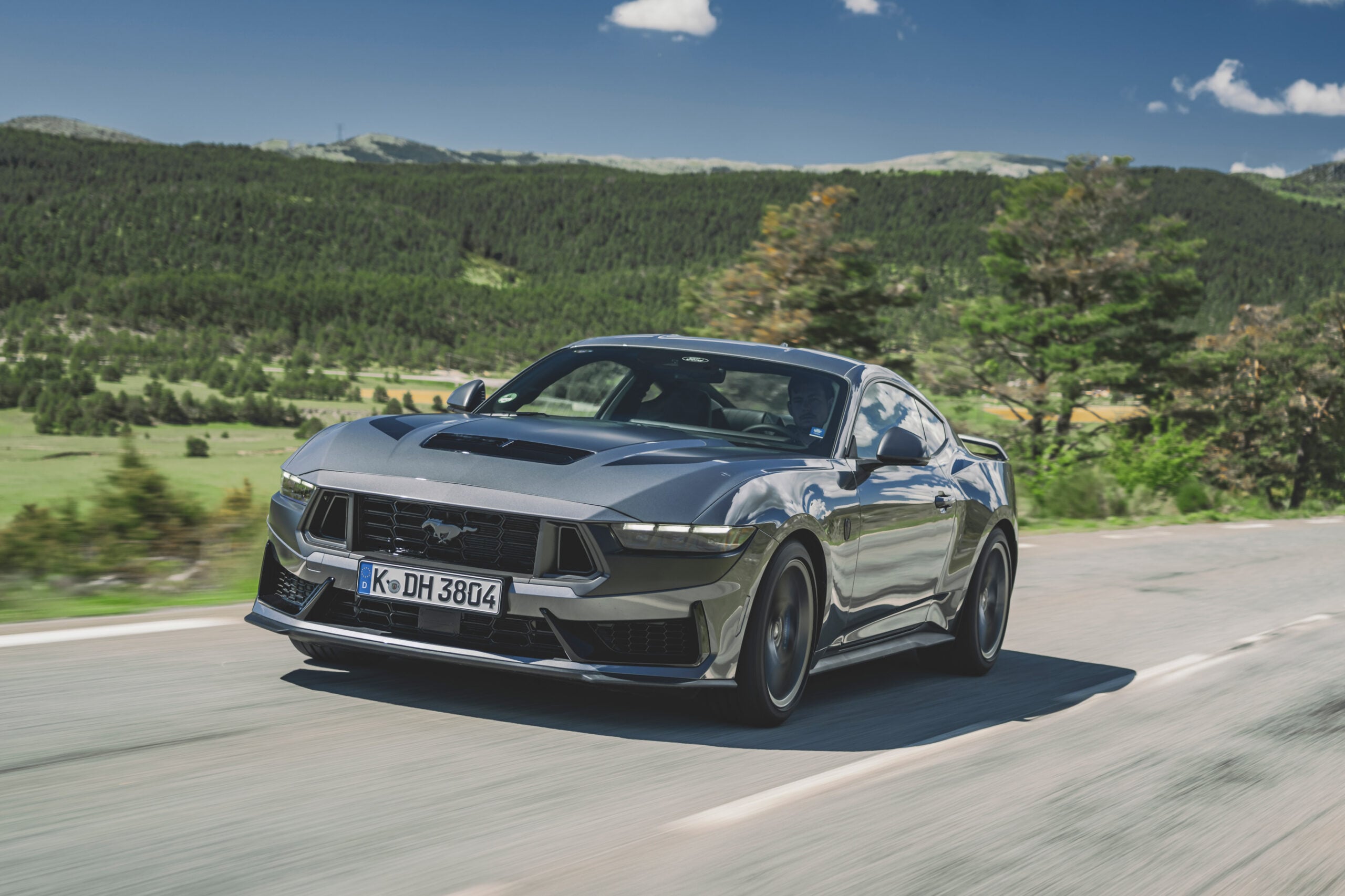 Official Ford photo of a Carbonized Gray Mustang Dark Horse side profile overlooking hills
