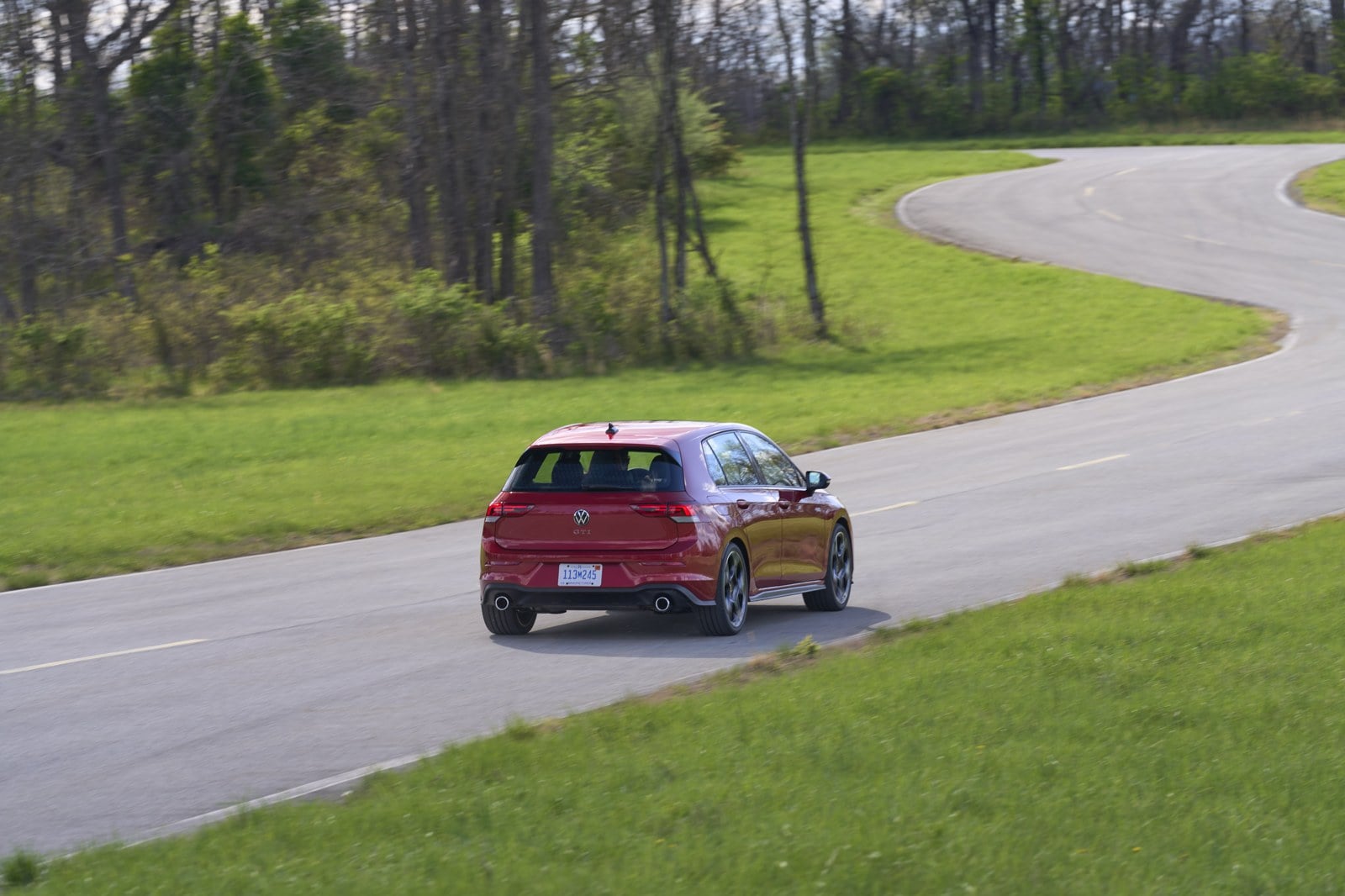 Official VW photo of 2025/2026 Golf GTI Autobahn rear three-quarter driving away in Kings Red Metallic