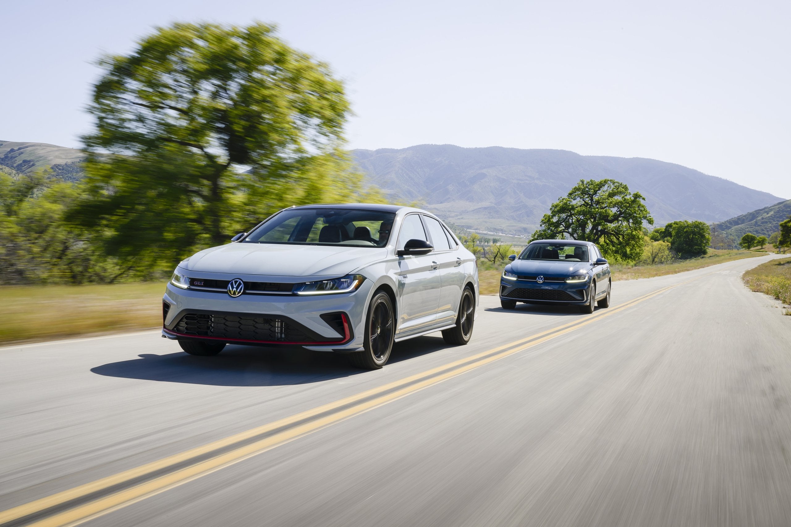 Official VW photo of Jetta GLI leading a blue Jetta on a rural road