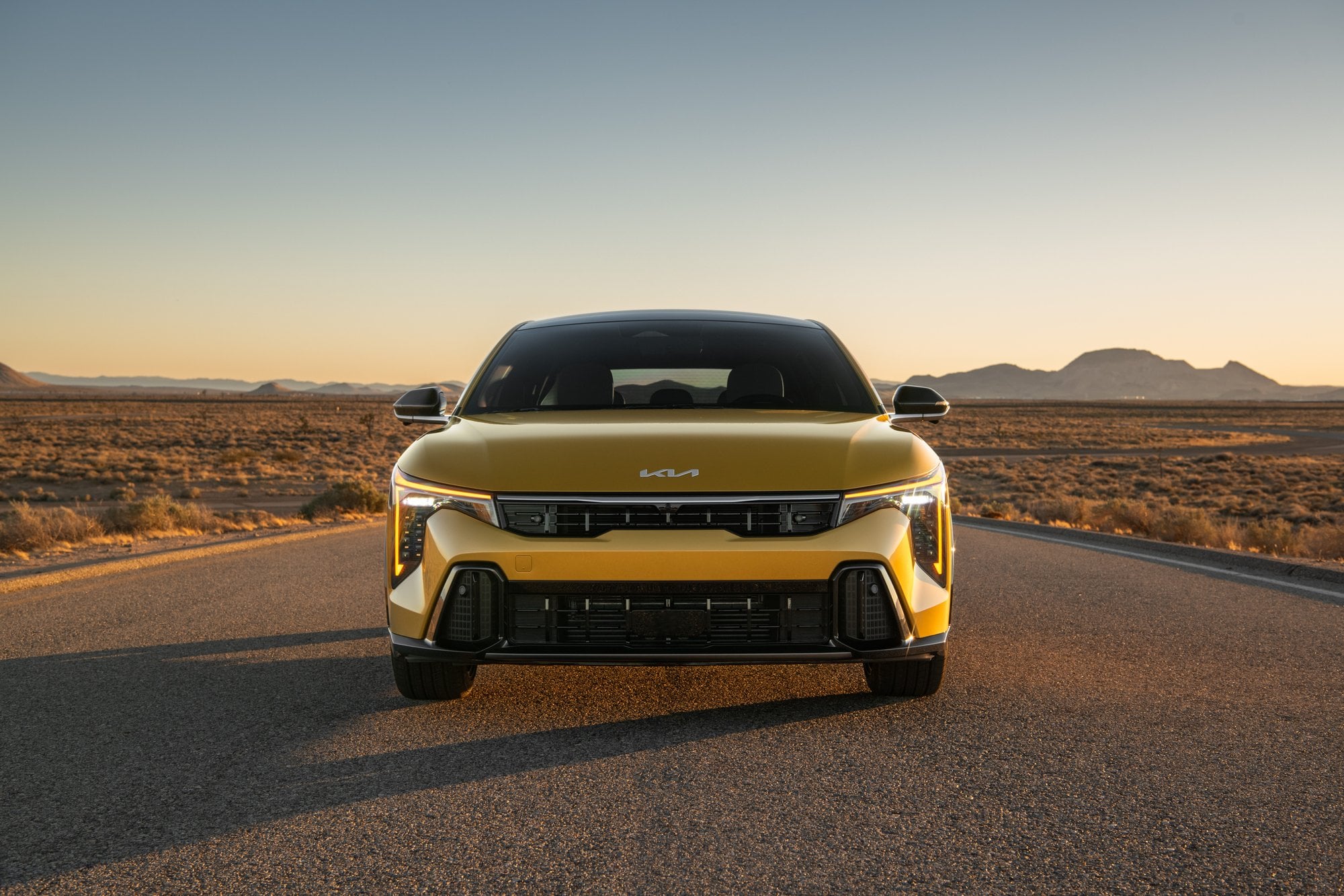 Official Kia photo of 2026 K4 Hatchback front view on a desert road at golden hour