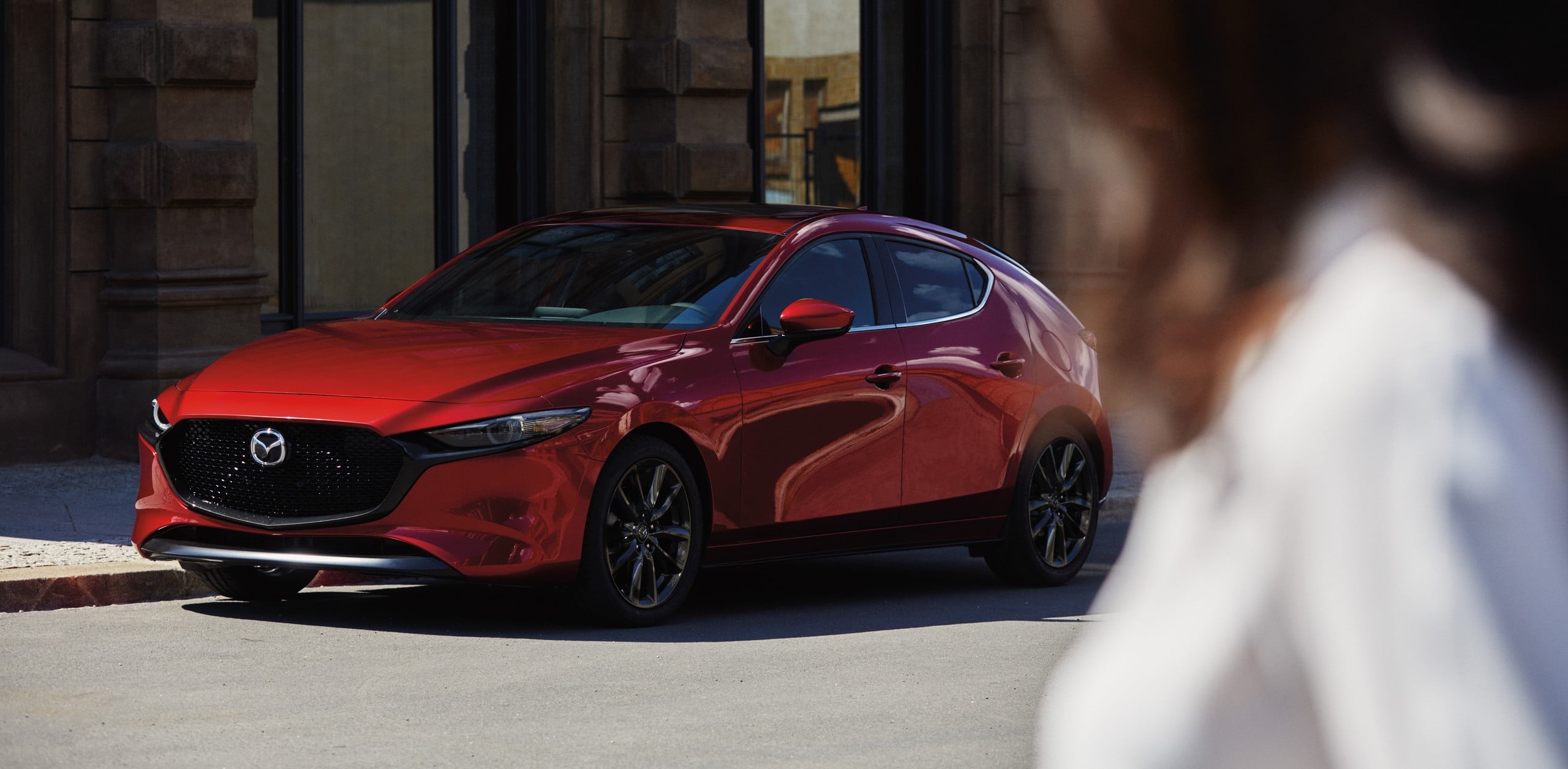 Official Mazda photo of a Soul Red Crystal Metallic Mazda3 Hatchback on a city street