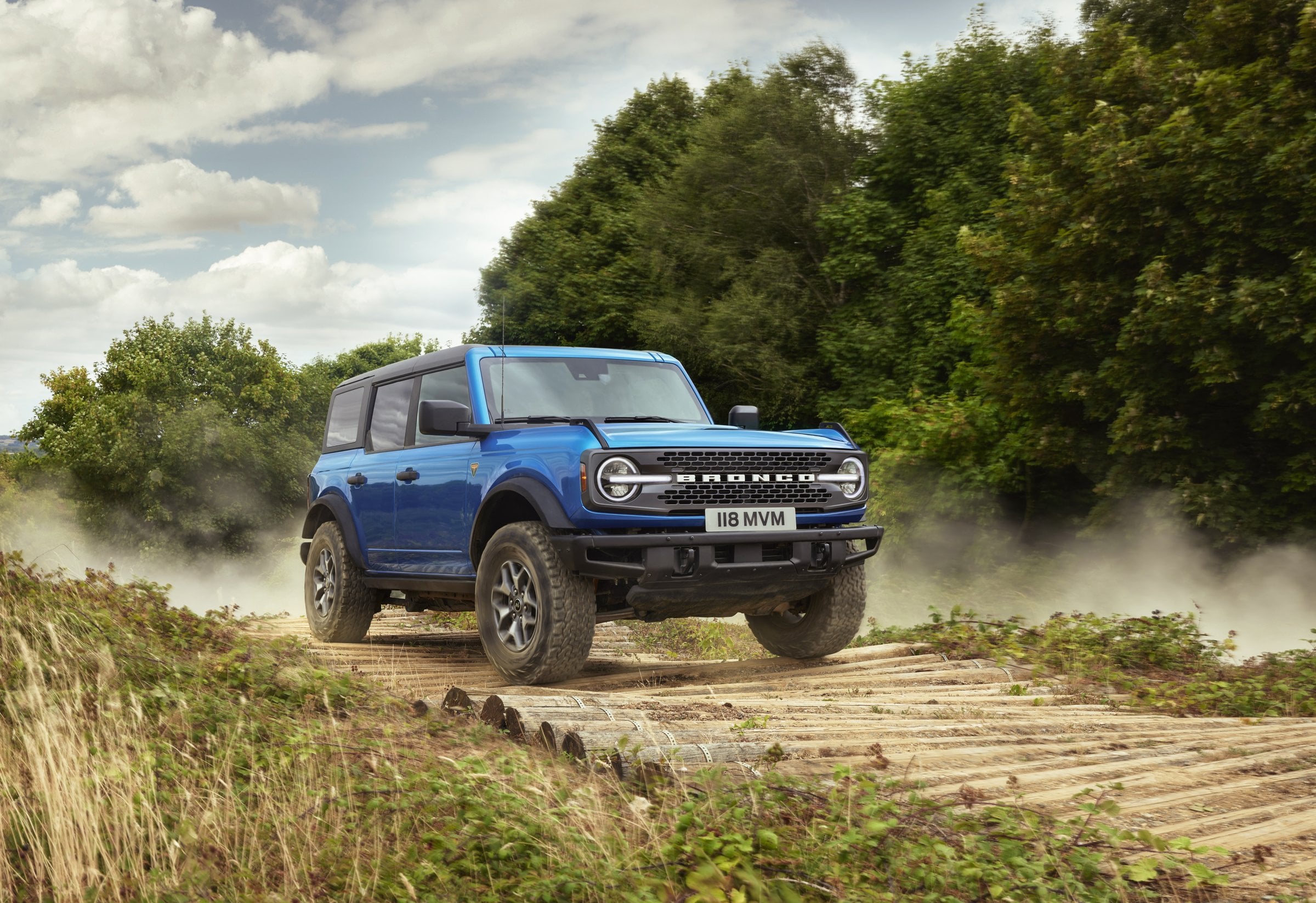 Official Ford press photo of a blue Ford Bronco Badlands four-door, front three-quarter in a grassy field