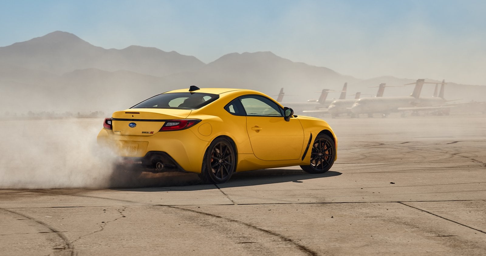 Official Subaru photo of a 2026 Subaru BRZ Series.Yellow kicking up dust as it slides on a dry lakebed, rear view
