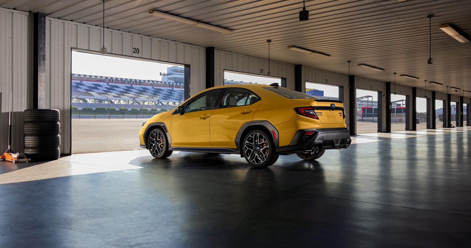 Official Subaru photo of a 2026 Subaru WRX Series.Yellow parked in a pit garage, rear three-quarter view