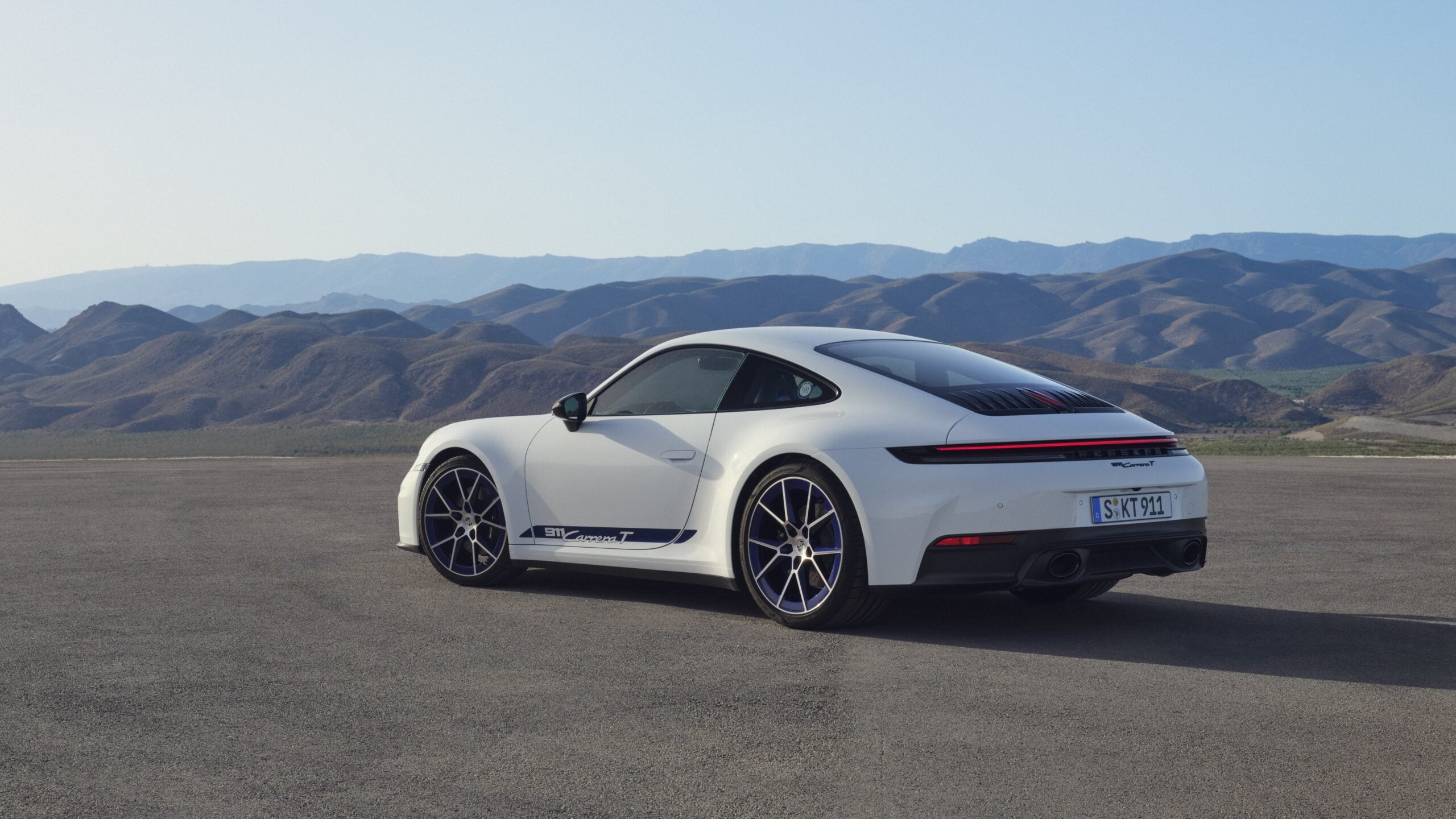Official Porsche photo of white 2027 911 Carrera T rear three-quarter with Carrera T side decal