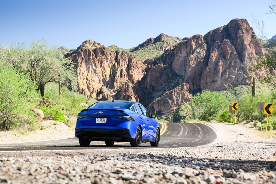 Official Nissan photo of a blue 2027 Nissan Sentra SR rear three-quarter curving along a mountain road