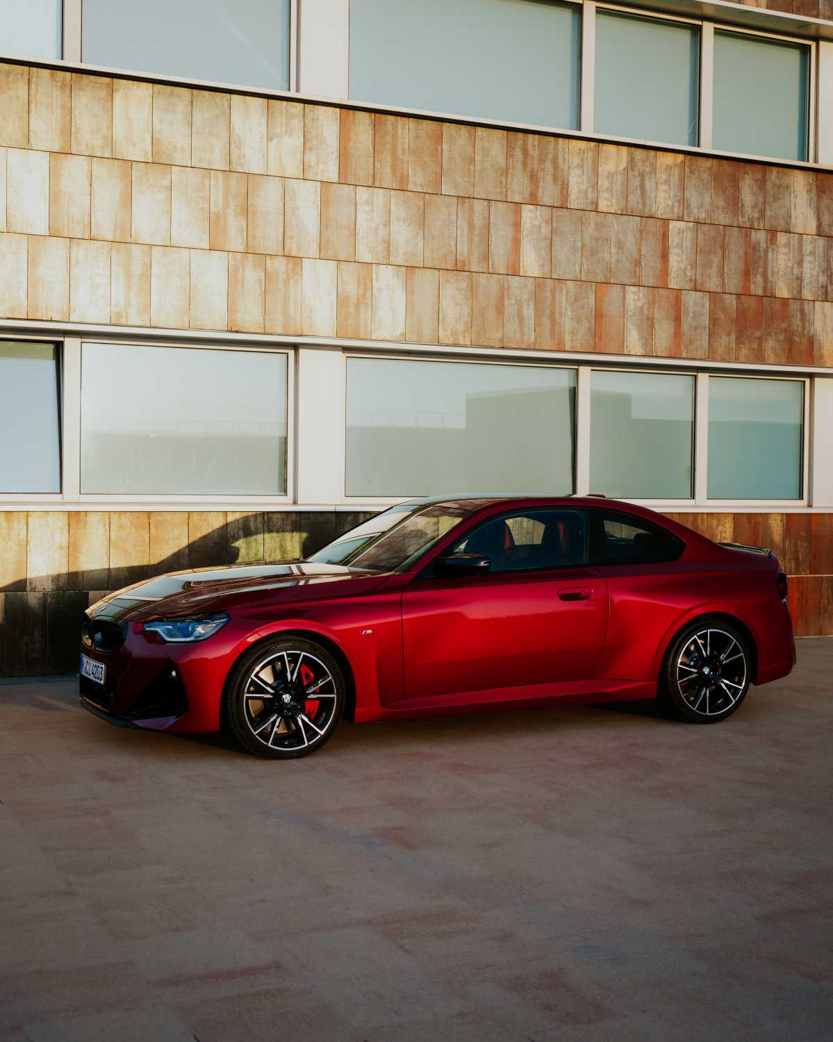Official BMW press photo of the BMW M240i Coupe side profile in metallic red