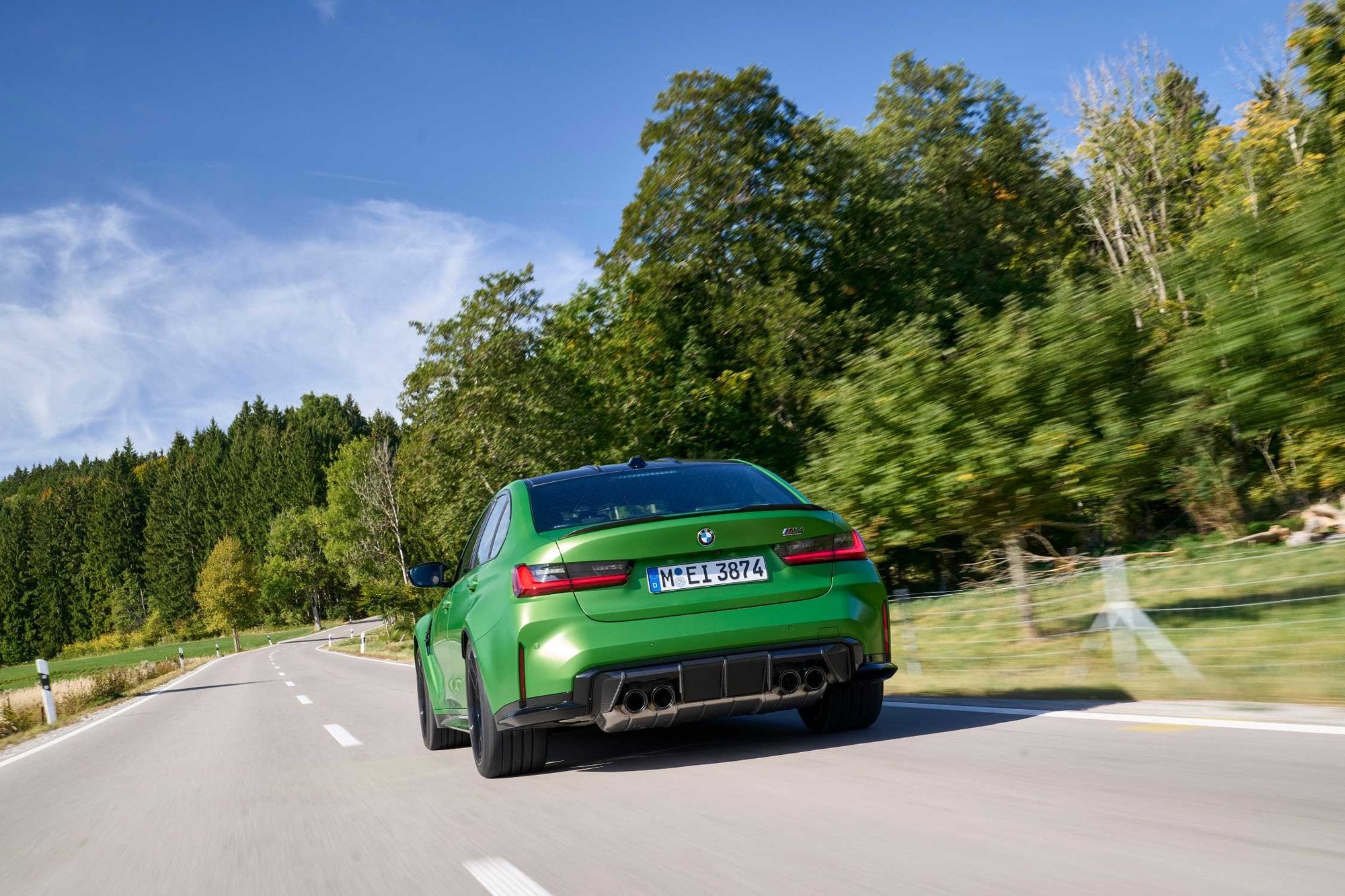 Official BMW press photo of the BMW M3 Sedan rear on a tree-lined road