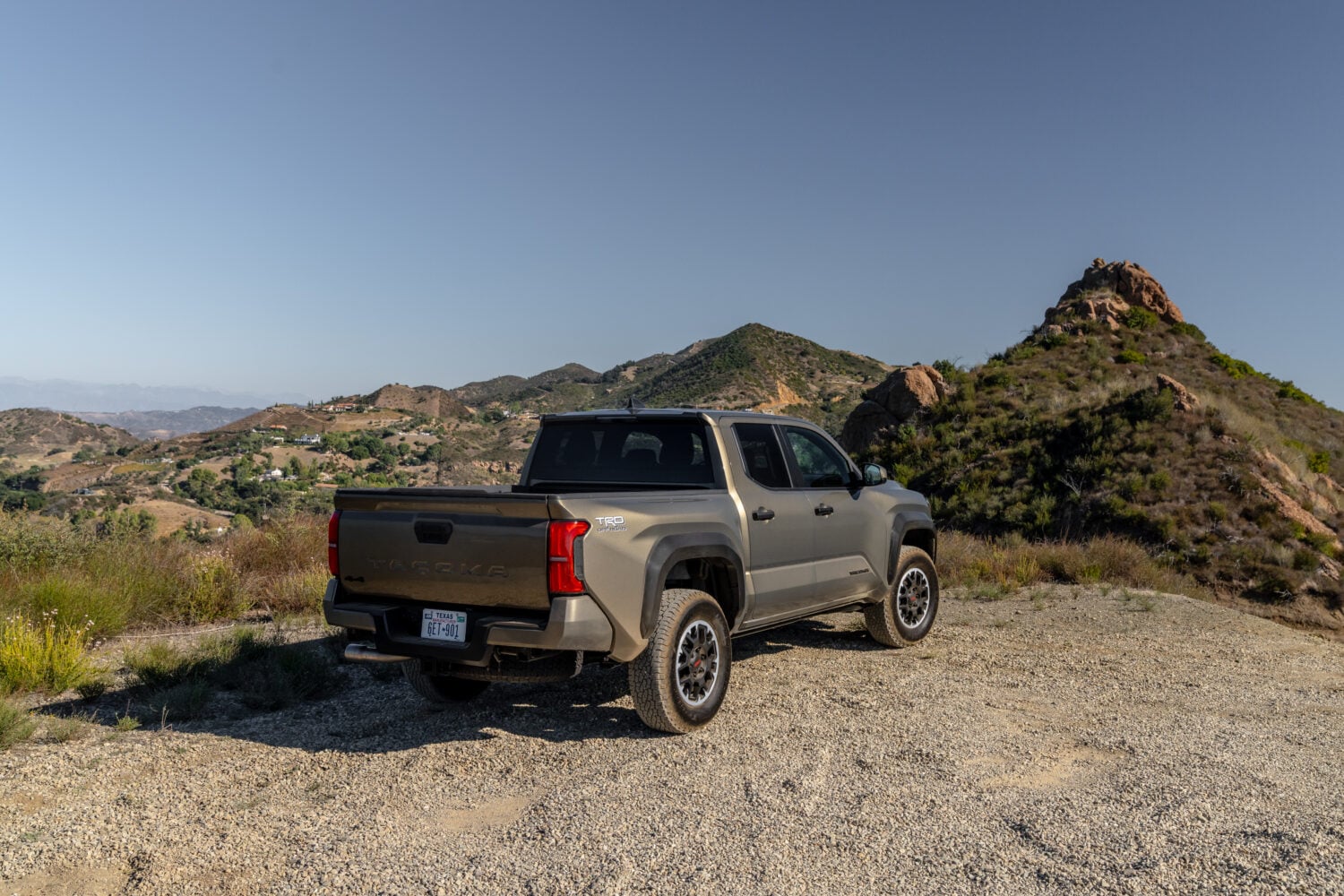 Official Toyota photo of a Tacoma TRD Off-Road Double Cab in Bronze Oxide, rear three-quarter in the hills