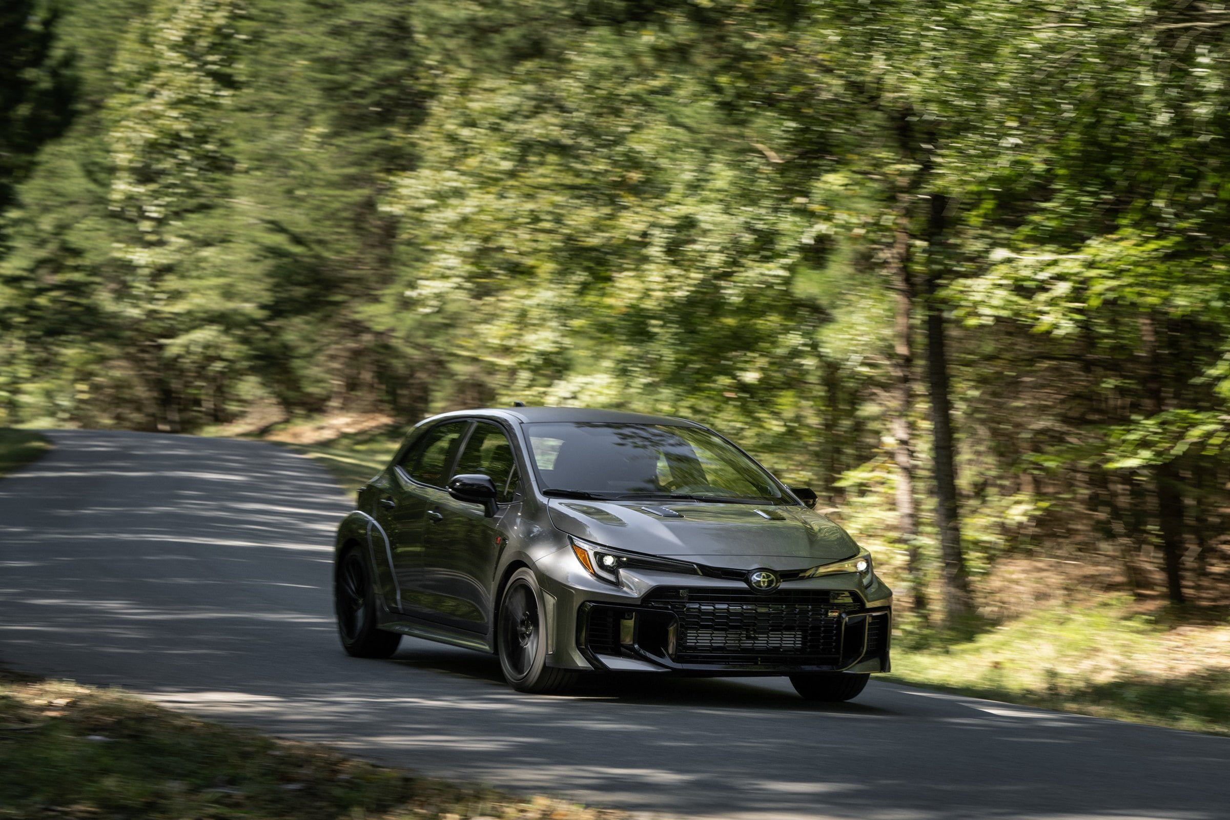 Official Toyota photo of the 2026 GR Corolla Premium Plus in Heavy Metal on a forest road