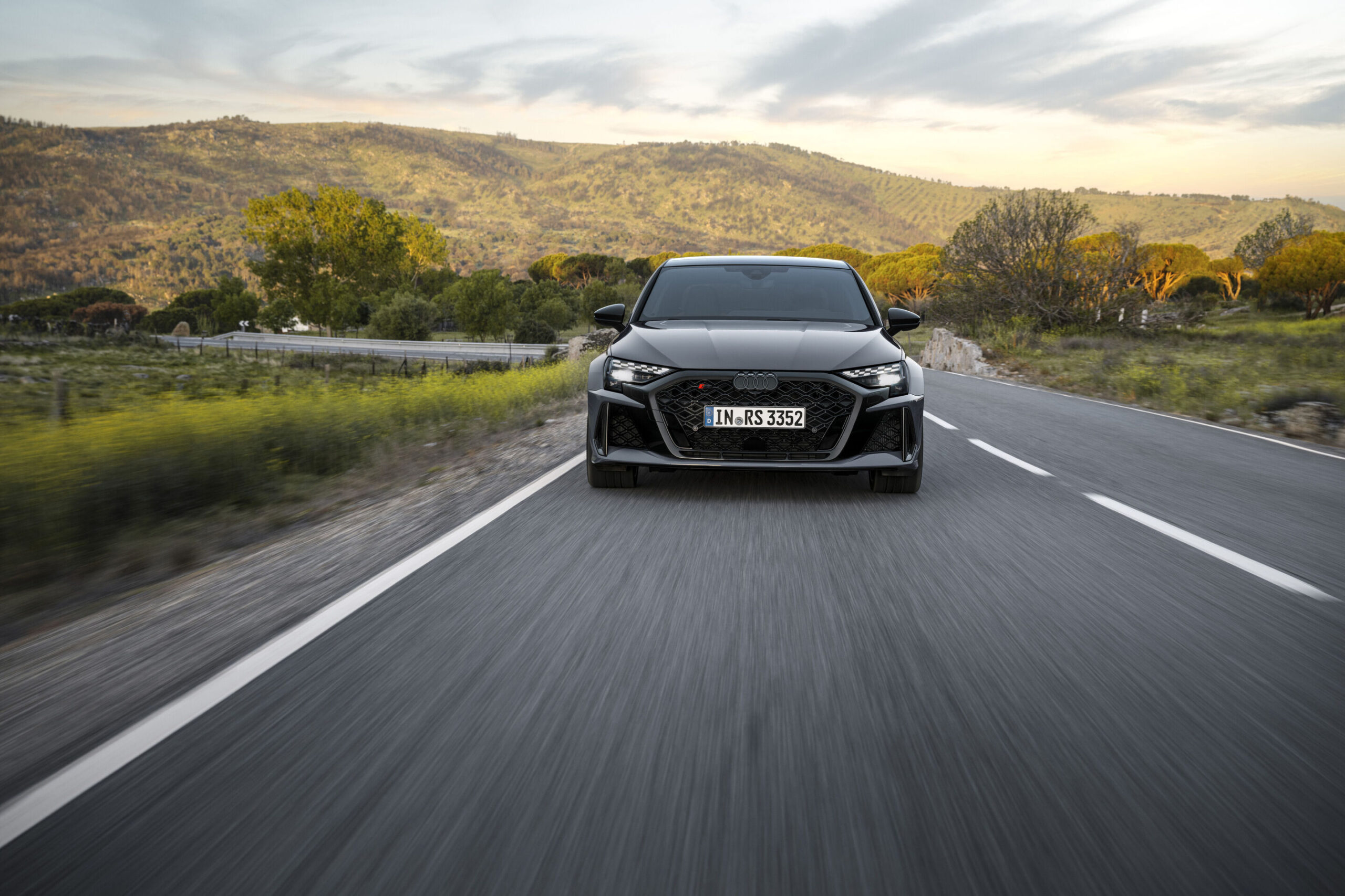 Official Audi photo of a Kemora Gray 2026 Audi RS 3 Sedan head-on in motion on a mountain road