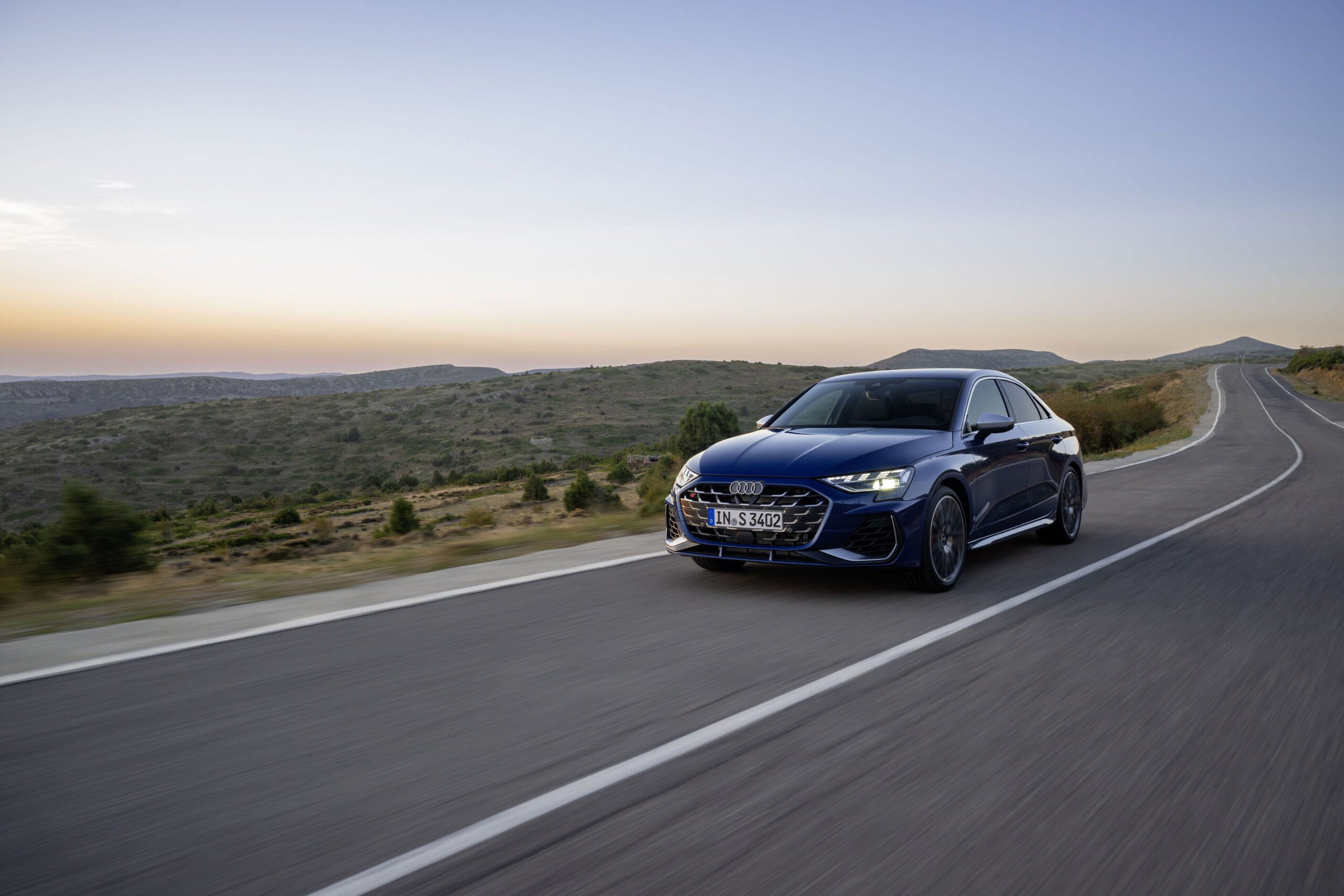 Official Audi photo of a dark blue 2026 Audi S3 front three-quarter in motion on a winding road