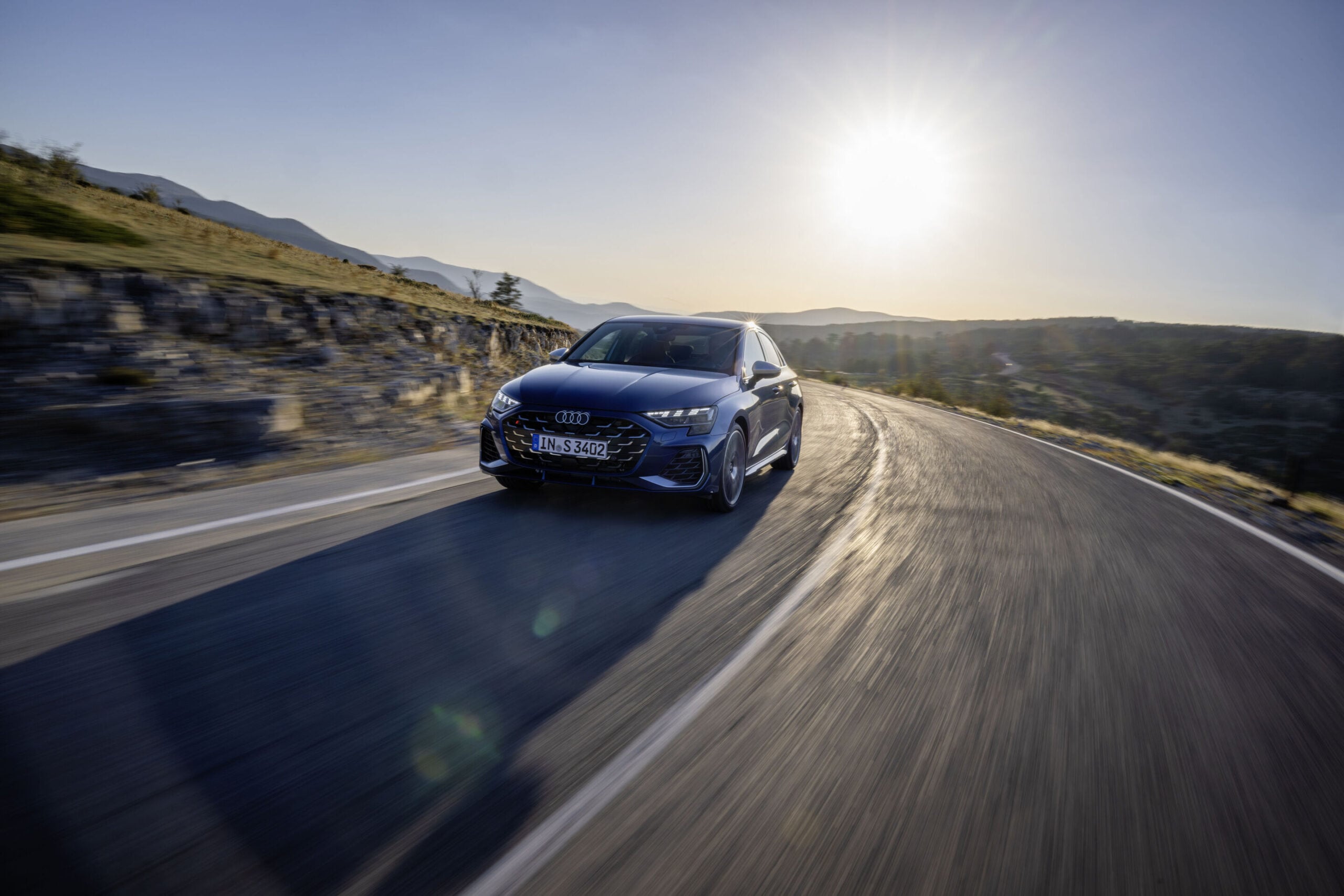 Official Audi photo of a dark blue 2026 Audi S3 front high-angle on a mountain road